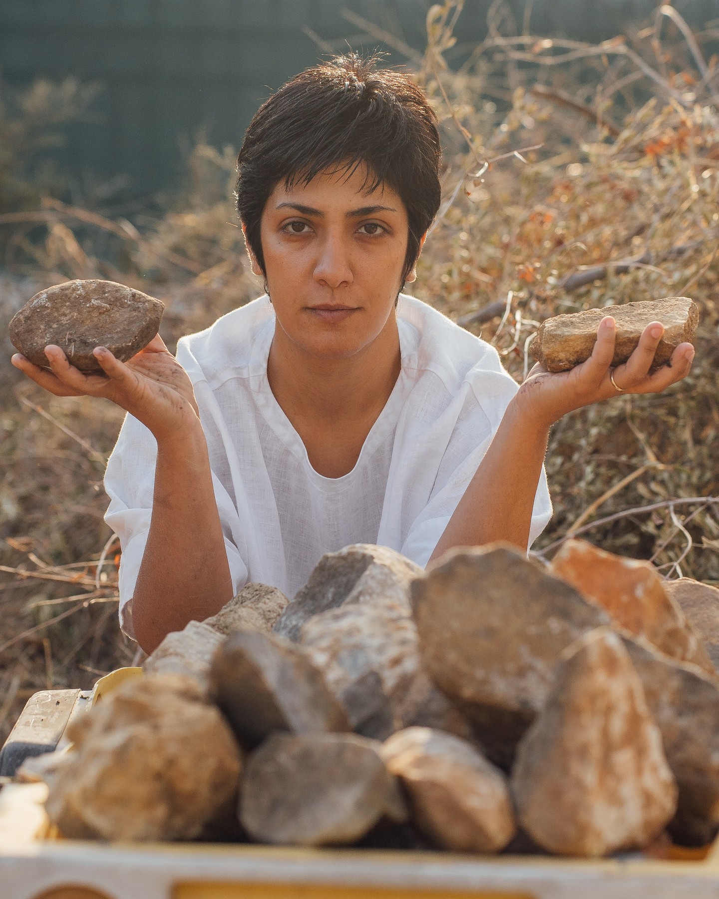 Trilogy of Eternal Condemnation
In my work, "Trilogy of Eternal Condemnation"—Atlas, Prometheus, and Sisyphus—I center condemnation, emphasizing how these figures exist on boundaries—physically, socially, or morally—while their suffering and rebellion define the struggles of humanity. Each represents those marginalized in society, whose suffering and defiance are crucial to collective resistance.
Atlas: The Burden of Oppression and Isolation
Peripheral to Society: Condemned to hold the heavens, Atlas stands on the edge of both divine and human realms, isolated by his eternal punishment. Stones, palm leaves, and skulls evoke isolation and reference the struggle of the oppressed.
Prometheus: The Price of Knowledge and Defiance
Peripheral to Power: Punished for gifting fire to humans, Prometheus symbolizes forbidden knowledge. Chains, charred trunks, bones, an eagle video, and liver meat convey his defiance.
Sisyphus: The Futility of Resistance
Peripheral to Achievement: Sisyphus, condemned to endlessly push a stone, is forever denied success. His struggle mirrors the relentless fight for justice faced by those on society’s periphery. A toy laborer’s car on a charcoal rail reflects the subtle joy in nihilistic repetition, bridging this heaviness with contemporary capitalist realities.
Parimah Avani (Artist, Writer, and Poet)
Parimah Avani (b. 1988, Tehran) is a nomad artist, writer, and poet with published works, books, and exhibitions. She gained a Master’s in Painting from the Fine Art Academy of Rome and a Ph.D. in Contemporary Art History from Sapienza University of Rome. A recognized voice in contemporary Persian hermetic literature and the avant-garde "Other" movement, her artistic journey is shaped by her travels and research in folk and political art. Her works address socio-political struggles, critiquing authority and environmental exploitation, using transparent and sustainable materials to explore how bodies become battlegrounds, invisible histories, and impact of oppression, the value of resistance, and unity.