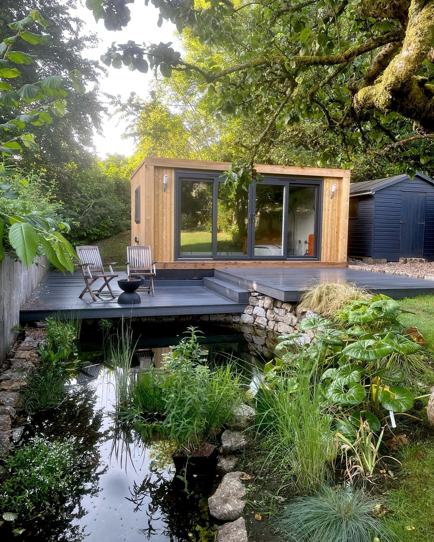 Love the finished look of this recently completed project, a perfectly balanced combination of contemporary functionality and rugged Dartmoor aesthetic.
We initially prepared the space ready for @greenretreats to install the garden room, then using local Dartmoor granite, built a new pond with sweeping walls to mirror the new borders and sunken seating area created elsewhere in the garden.
To maximise the available space, we installed striking slate grey @neotimber composite decking, aligning the different levels of the area to keep the lines clean and sleek, and created a small platform overhanging the edge of the pond to merge the two features.
We chose architectural planting with a simple colour scheme of green, white, and indigo tones. More to follow… #chagford #dartmoor #garden #gardendesign #decking #devon #pond