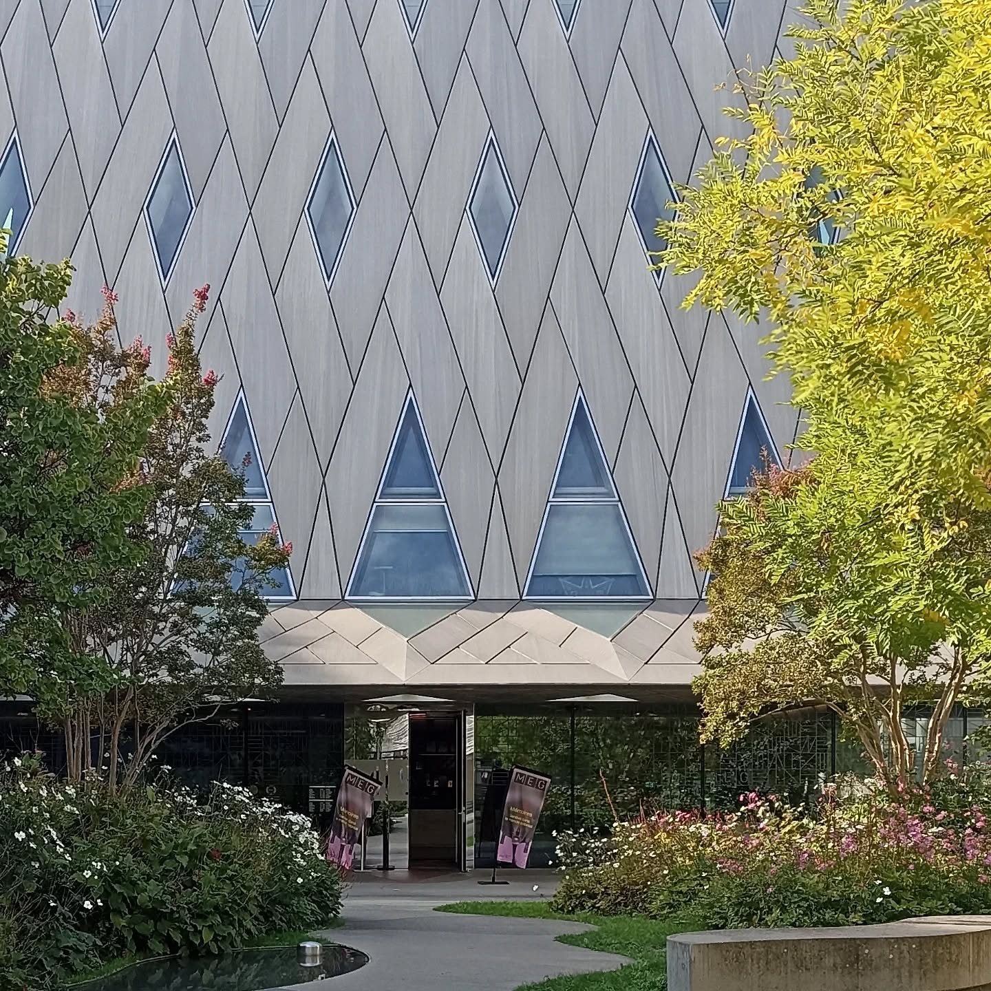 Le Musée d’ethnographie de Genève (MEG) est un exemple marquant d’architecture contemporaine à Genève, alliant modernité et intégration urbaine. Inauguré en 2014, le bâtiment principal se distingue par sa forme sculpturale et son toit plissé évoquant une tente ou une vague, en référence aux cultures du monde qu’il abrite.
Le projet a été conçu par le bureau d’architecture Graber & Pulver Architekten, en collaboration avec Brodbeck Roulet Architectes Associés. Leur approche a consisté à créer un lieu ouvert et accueillant, avec une grande esplanade publique qui relie le musée à la ville. L’usage de matériaux contemporains, comme le béton et le métal, contraste avec les bâtiments environnants tout en respectant l’échelle du quartier.
À l’intérieur, les espaces sont conçus de manière flexible pour accueillir des expositions variées, avec une attention particulière portée à la lumière et à la circulation des visiteurs. Le MEG illustre ainsi une architecture au service du contenu, où la forme et la fonction dialoguent pour valoriser les collections ethnographiques.
#MEG #MuséeEthnographieGenève #Genève #ArchitectureContemporaine #ArchitectureSuisse #GraberPulver #Musée #Culture #DesignArchitectural #EspacePublic #ArchitectureEtCulture