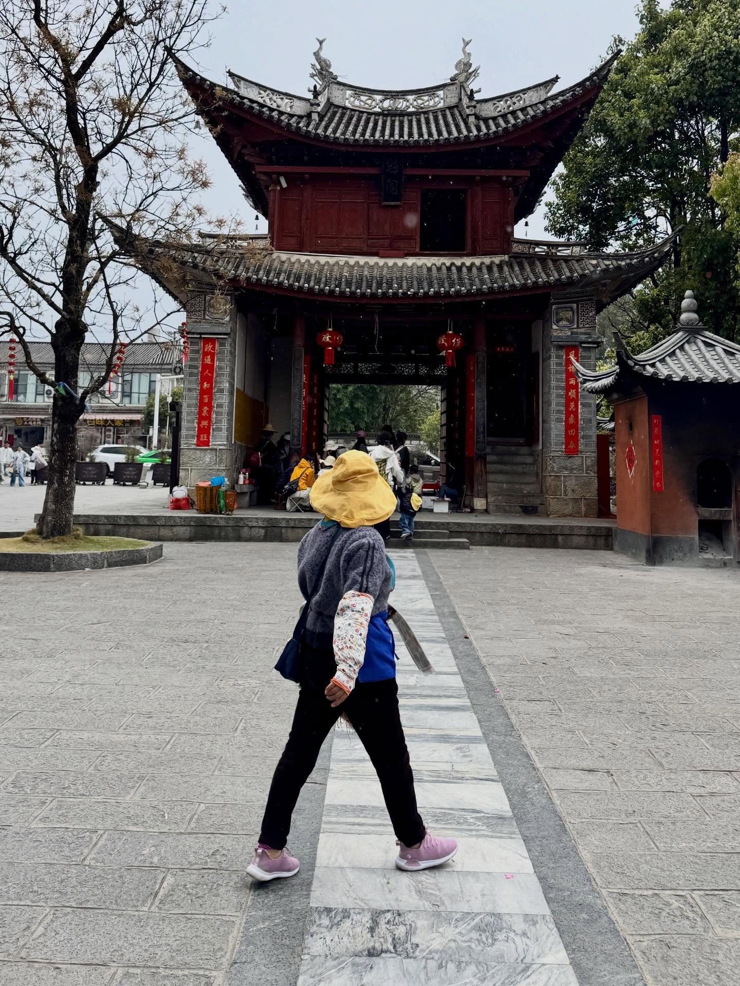 Tranquility lost as we crash into tourist crowd mania in Xizhou. In the rain. Nothing for it but to shelter in a noodle bar, eat the local stuffed flatbreads and take an unusually long interest in a historical house.
After the rain clears I get lost and stumble out of the labyrinth and find myself in a shock of green paddy framed by mountains. And the sun comes out finally.
Of course someone has built a toy train to allow tourists to ride round the paddy.
Dali is Old Town is a socialising hot spot, clamouring honk of horns from e-scooters and cars and toes in danger as we jostle for space. Vibrant shops and food stalls observed from ancient city wall watch towers.