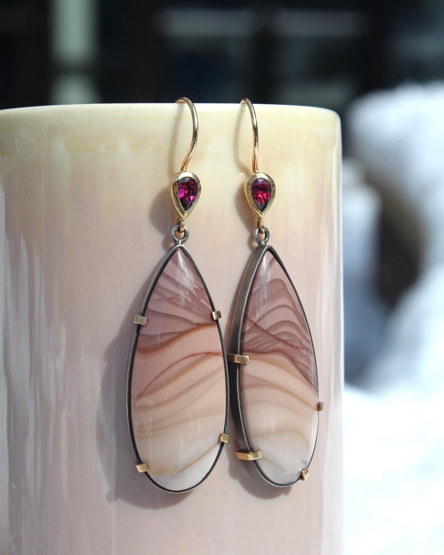 Large pear shaped drops of Idaho jasper are held in gold prongs, wrapped in oxidized sterling silver and topped with rhodolite garnet in these statement making earrings by local sweetheart @karinjacobsonjewelry ✨🩷