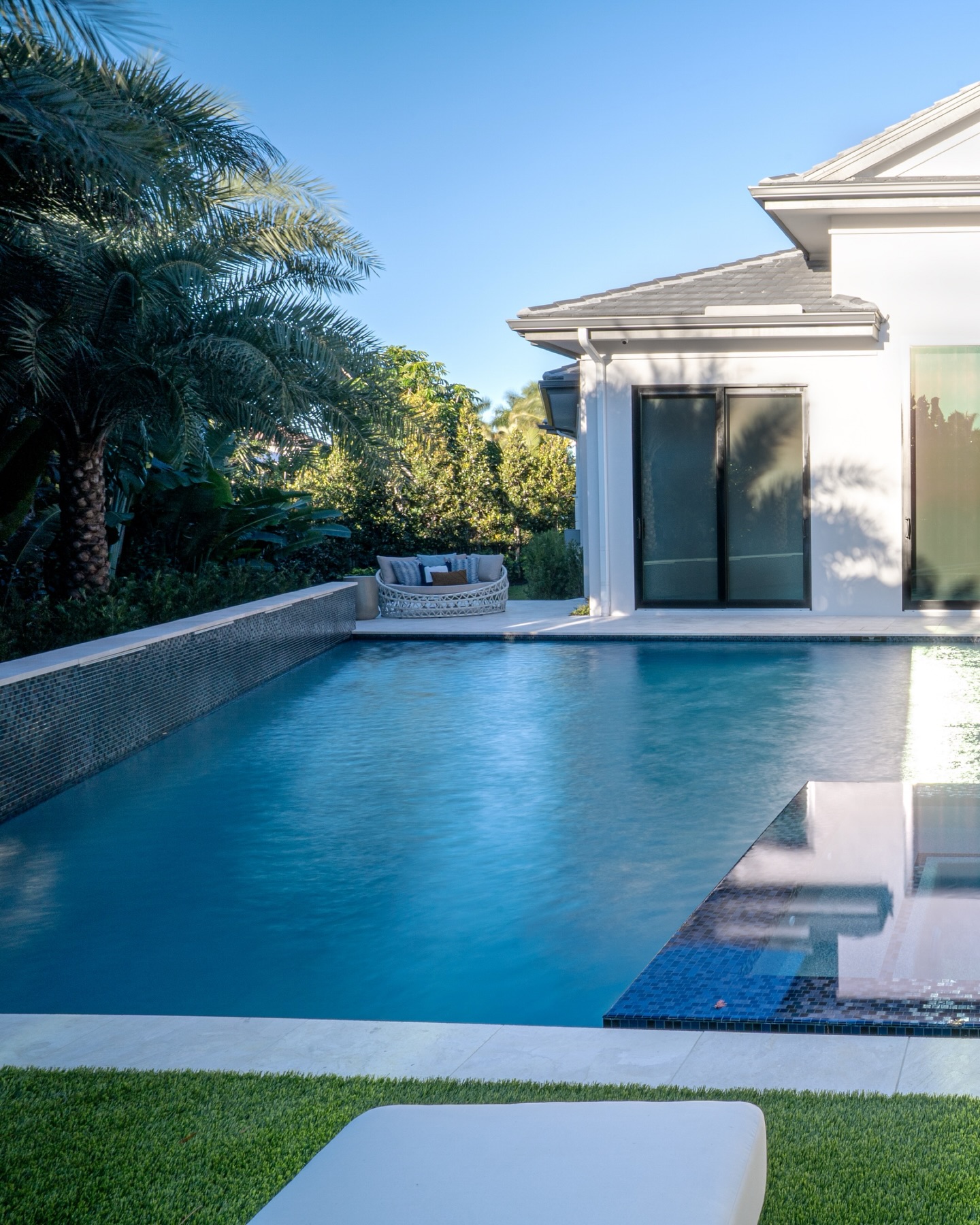 A study in levels and stillness.
A deck-level spa mirrors the architecture, while the sun shelf floats just below, lined with loungers and softened by rhythmic bubblers. Turf underfoot adds a clean, coastal contrast to the stone.
#NaplesLuxuryHomes #OutdoorLivingDesign #LuxuryPoolDesign #CoastalModern #FloridaDesign