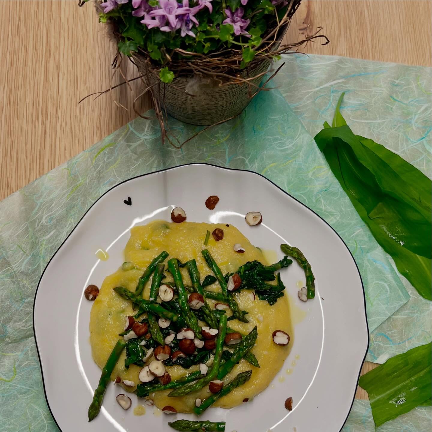 Cremige Polenta mit grünem Spargel, Bärlauch & Haselnüsse
Der Frühling schmeckt genauso: grün, frisch und ein bisschen nussig.
Diese cremige Polenta ist ein echtes Wohlfühlgericht – unkompliziert, aber voller Aroma. Zarter Spargel trifft auf würzigen Bärlauch, dazu geschmolzener Gruyèrekäse und crunchy Haselnüsse obendrauf.
Ein Gericht, dass sich nach wenig Aufwand anfühlt, aber nach viel mehr schmeckt.
Perfekt für Tage, an denen du etwas Warmes brauchst, das trotzdem leicht bleibt.
Zutaten für 2 Personen:
Polenta:
500 g grüne Spargeln, Spitzen beiseitelegen
- Rest in ca. 5 mm dicke Scheiben schneiden
1 EL Olivenöl
1 TL Salz
4 dl Wasser
75 g mittelfeiner Maisgriess
Topping & Finish:
2 Bund Bärlauch (ca. 40 g), grob geschnitten
120 g geriebener Gruyère Käse
60 g Haselnüsse, geröstet & grob gehackt
Salz & Pfeffer
Zubereitung:
Olivenöl in einer Pfanne erwärmen. Die Spargelscheiben dazugeben, salzen und kurz (ca. 1 Minute) andämpfen.
Wasser dazu giessen und aufkochen lassen.
Maisgriess unter Rühren einrieseln lassen und bei kleiner Hitze etwa 4 Minuten köcheln lassen, bis eine cremige, dicke Polenta entsteht.
Zugedeckt warm halten.
In einer beschichteten Pfanne etwas Olivenöl erhitzen.
Die Spargelspitzen darin rund 5 Minuten rührbraten, bis sie leicht gebräunt und noch bissfest sind.
Salzen, dann den Bärlauch kurz mitbraten – nur so lange, bis er zusammenfällt und intensiv duftet.
Den Gruyère Käse unter die warme Polenta rühren, bis er schön schmilzt.
Mit Salz und Pfeffer abschmecken.
Polenta in Schalen anrichten, Spargelspitzen und Bärlauch darauf verteilen.
Mit etwas Olivenöl beträufeln und mit den gerösteten Haselnüssen toppen.
Tipp:
Wenn du Gäste hast: Serviere das Ganze in einer grossen Schüssel in der Mitte und lass alle selbst nehmen – wirkt direkt wie ein gemütliches Frühlings-Dinner.
@thekitchenwitches #bärlauch #polenta #vegetarisch #vegan #rezepte