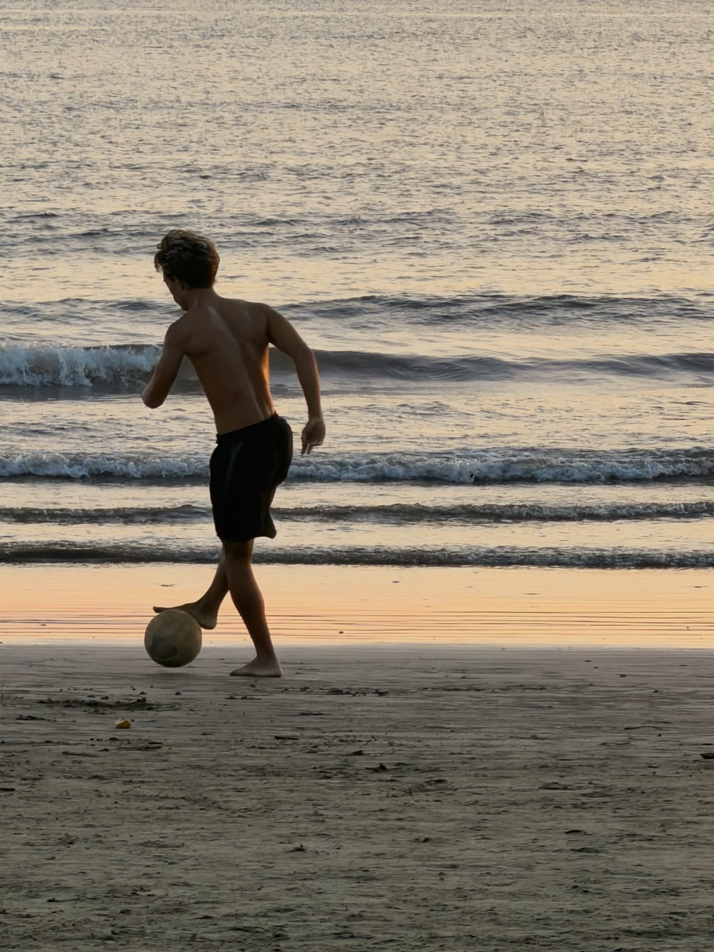 A luz desce devagar,
tingindo a areia de laranja e sal.
Um menino e uma bola —
o resto do mundo, opcional.
Toca. Levanta. Equilibra.
O corpo aprende sozinho a falar
numa língua sem palavras,
que só o mar sabe escutar.
A bola sobe, suspensa,
entre o céu e a espuma e o vento —
um instante que não pede
nem memória nem movimento.
O rosto erguido, os olhos no alto,
como quem reza ou quem deseja:
que a bola volte, que o dia dure,
que a vida seja sempre essa.
O pôr do sol não tem pressa.
Sabe que não vai perder:
toda pelada na praia
termina quando quiser.
#poesia #poesiabrasileira #trabalhoautoral
#arteempalavras #poem