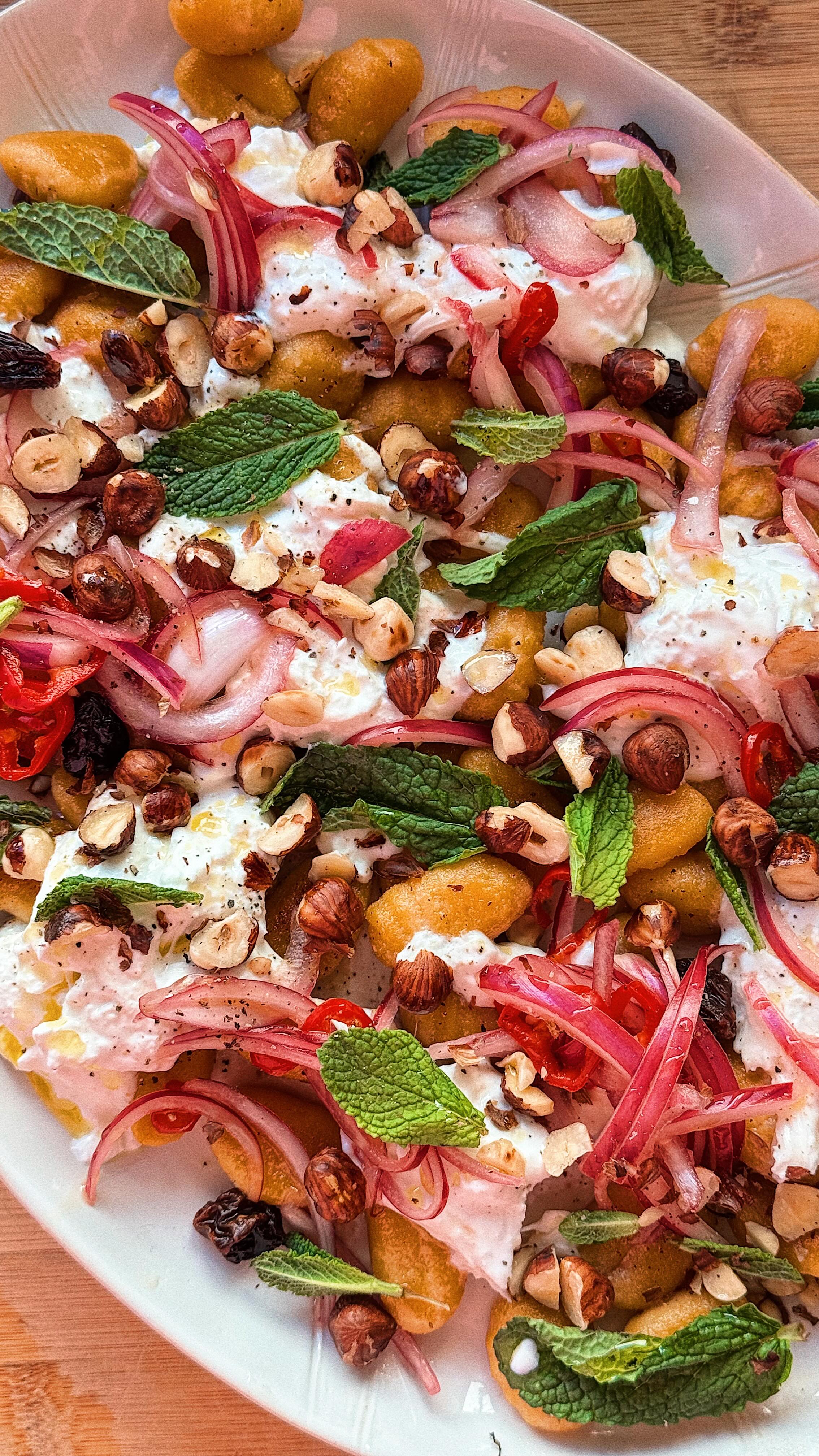 Welcome to the fourth and final episode of our International Women’s Day Series, championing other incredible women and female-founded brands that we love
In this episode we are highlighting the face behind this series, @izziemcox , who is the brains and the hands behind these wonderful recipe videos. Being an all-female team, we couldn’t think of a better way to close this series than by turning the spotlight on Izzie. Her creativity, passion, and talent have brought this series to life, and we are proud to champion her alongside all the incredible women we’ve featured.
Crispy and tangy, this salad is a brilliant way to welcome the beginnings of Spring, and beautifully combines sweet and savoury with an array of textures and flavours.
Here’s the recipe:
Crispy pumpkin gnocchi salad with burrata🥗
Serves 2
2 tbsp red wine vinegar
1 tbsp honey
1/2 red onion, finely sliced
1 red chilli, finely sliced
1 tbsp raisins or currants
30g hazelnuts
1 tbsp extra virgin olive oil
250g @sunnyandlunaeats pumpkin gnocchi
1 burrata, torn
10g fresh mint, leaves picked
sea salt and finely ground black pepper
Heat the red wine vinegar, honey, 1 tablespoon of water and salt and pepper in a small pan on a medium heat for a couple of minutes until well combined.
Add the red onion, chilli and raisins to a bowl and pour over the vinegar mix. Toss well to combine and set aside for 15 minutes.
Meanwhile, heat a frying pan over a medium heat and toast the hazelnuts for a few minutes until golden and fragrant. Transfer to a bowl and set aside.
Return the pan to the heat with the gnocchi and cook for 6 minutes, turning often, until golden and crisp.
Add the gnocchi to a large platter and tear over the burrata. Pour over the red onion dressing, hazelnuts and finish with the mint leaves.