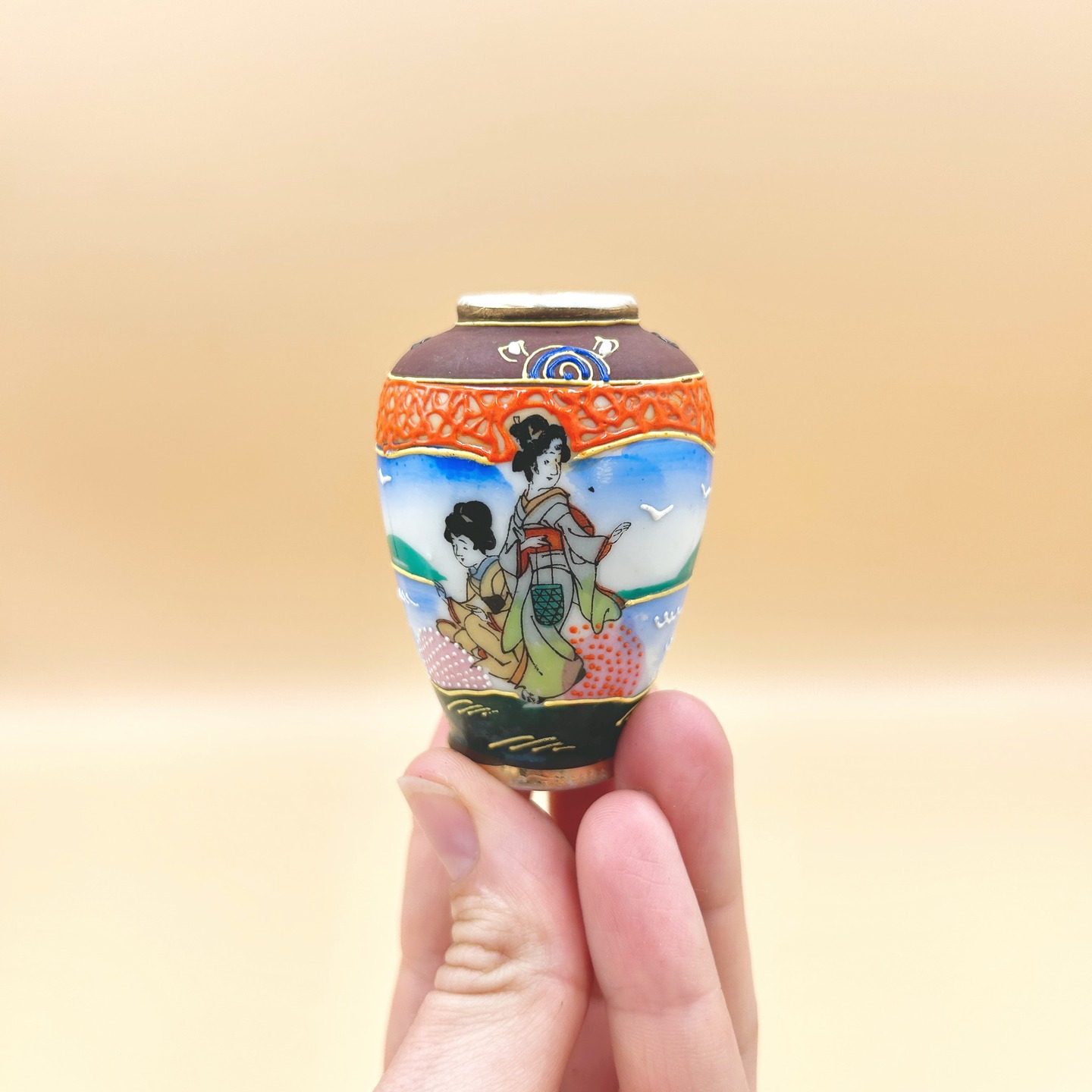 ❌ SPRZEDANY | Mikro wazonik, Japonia, lata 60-80. XX w.
Mikroskopijnych rozmiarów wazonik solifiore w stylu satsuma revival, częściowo ręcznie dekorowany, a częściowo zdobiony metodą transfer print. Dekoracja przedstawia Japonki w tradycyjnych strojach i uczesaniach.
Satsuma revival odnosi się do odrodzenia i reinterpretacji stylu ceramiki satsuma w Japonii pod koniec XIX i na początku XX wieku, szczególnie w kontekście produkcji eksportowej po okresie Meiji. W tym czasie warsztaty zaczęły masowo wytwarzać wyroby o charakterystycznej, bogato zdobionej powierzchni z użyciem złocenia i drobnych, precyzyjnych dekoracji figuralnych oraz ornamentalnych. Revival ten miał w dużej mierze charakter komercyjny i odpowiadał na zachodni popyt na „egzotyczną” estetykę Japonii, co wiązało się z pewną standaryzacją i stylizacją motywów.
W latach 50.–60. XX wieku nastąpiła kolejna faza tzw. Satsuma revival, tym razem silnie związana z powojenną produkcją eksportową, zwłaszcza na rynek amerykański. Wyroby z tego okresu cechują się uproszczoną techniką, często z użyciem kalkomanii i mniej precyzyjnego złocenia, przy jednoczesnym zachowaniu charakterystycznej, „gęstej” ornamentyki i ikonografii (sceny dworskie, gejsze, motywy figuralne).
Stan idealny.
Wys. 7 cm
35 PLN + 15 PLN koszt wysyłki