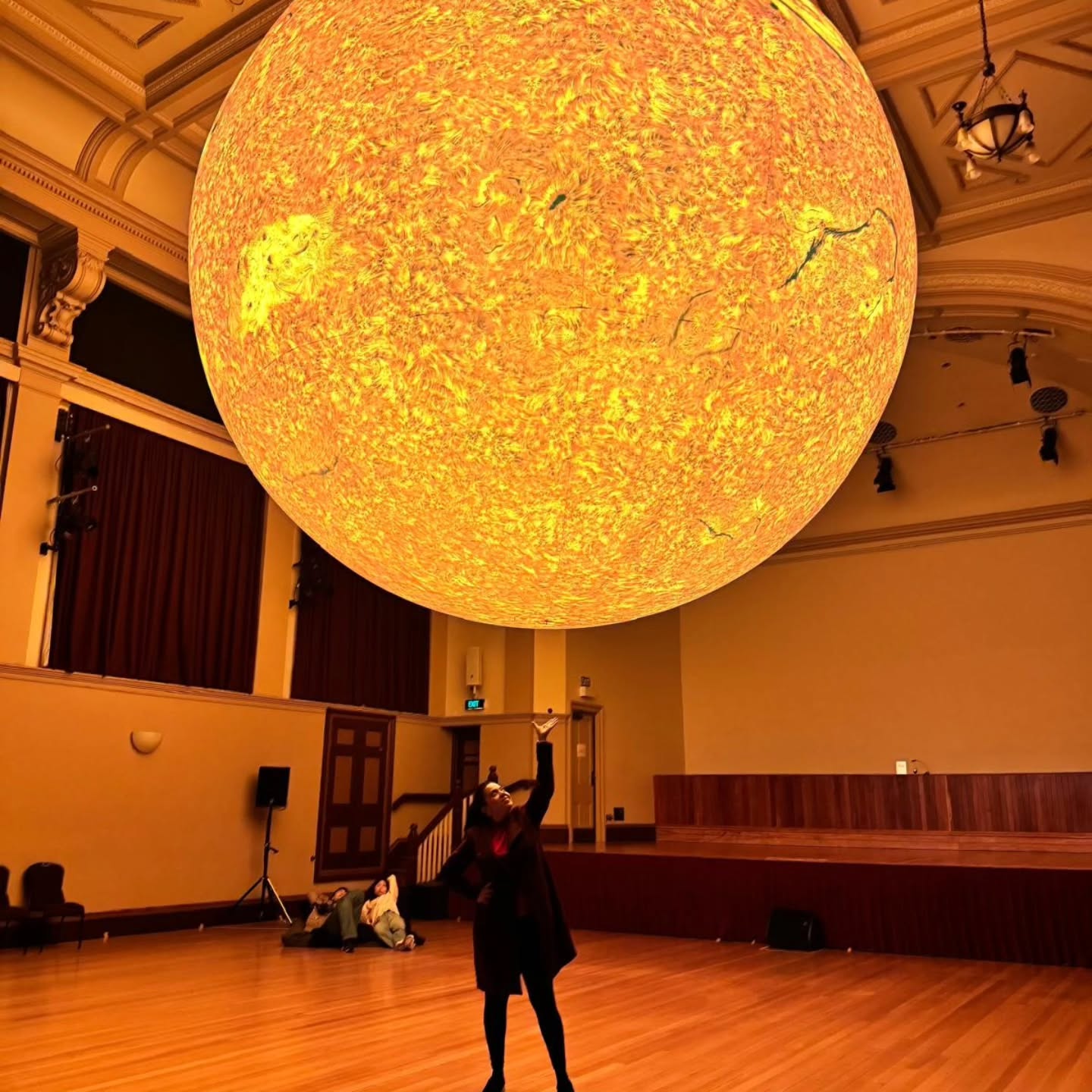 El evento Helios fue una exposición de arte visual que formó parte del Auckland Arts Festival, uno de los festivales culturales más importantes de la ciudad. Se llevó a cabo del 7 al 15 de marzo de 2026 en la Cámara de Conciertos del Auckland Town Hall.
La obra fue creada por el artista británico Luke Jerram y consistió en una instalación gigante que representaba al Sol. Esta pieza combinó arte y ciencia, permitiendo a los visitantes experimentar de forma inmersiva la escala, los detalles y la complejidad de nuestra estrella más cercana. Además, durante algunos días hubo presentaciones musicales en vivo a cargo de la Auckland Philharmonia, lo que hizo la experiencia aún más sensorial. Lo mejor era GRATIS! Para màs de #NuevaZelandaEnEspañol checa mi página www.latinkiwi.com o en mis historias donde las aviso de estos eventos y más ! #AucklandCity #Latinkiwi #visitauckland #explorenz