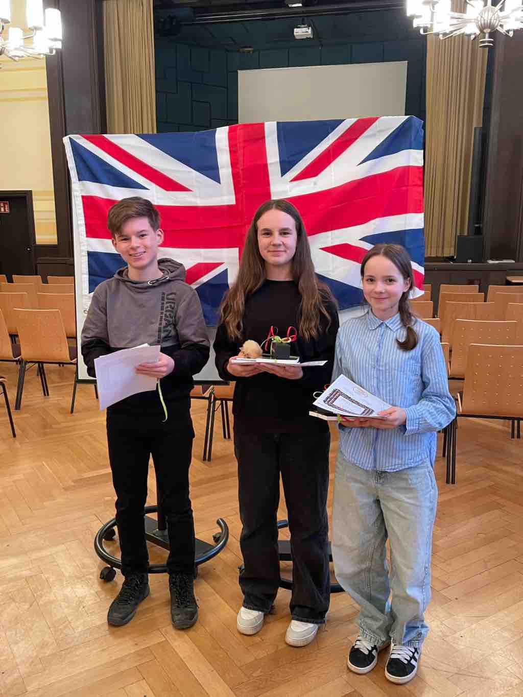 📚🇬🇧 Vorlesewettbewerb Englisch 🇬🇧📚
Am vergangenen Donnerstag fand von 14:00–16:00 Uhr der Englisch-Vorlesewettbewerb in der Aula des AGC Chemnitz statt. Insgesamt traten 7 Schülerinnen und Schüler der Klassenstufe 7 an – 3 vom CGG und 4 aus Chemnitz.
Gelesen wurde sowohl ein bekannter als auch ein unbekannter Text – eine echte Herausforderung für alle Teilnehmenden! 👏
Die Jury, bestehend aus Englischlehrern aus Chemnitz und Kirchberg, bewertete die Vorträge. Die Eröffnung sowie die anschließende Siegerehrung wurden von Schulleiter Herrn Gläser übernommen. 🏆
Unterstützt wurden die Teilnehmer von einigen Eltern und Lehrern aus Chemnitz im Publikum.
Herzlichen Glückwunsch an alle Beteiligten – starke Leistungen auf ganzer Linie! 💬✨
#vorlesewettbewerb #englisch #bili #graupnergym