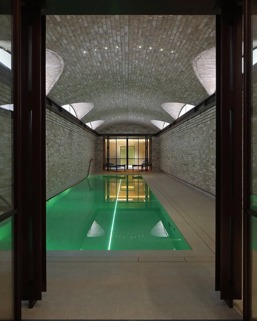 A vaulted brick ceiling forms the architectural centrepiece of this pool space. Integrated spotlights sit within the brickwork, casting a soft glow that highlights the texture and curvature of the vault.
Interiors: @charlesrutherfoorddesign
Image 2 captured by James Balston