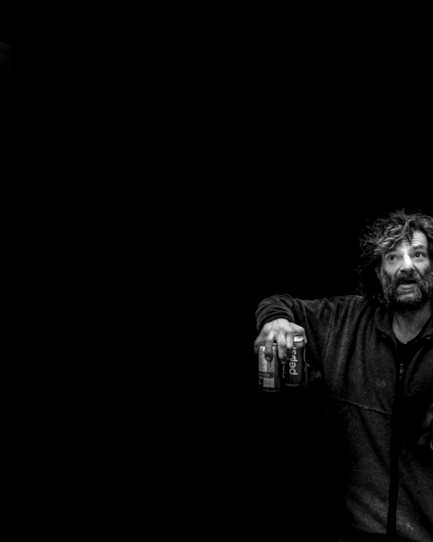 A hand appears in the dark offering sugar and bubbles like it’s no big deal.
The mind says “stranger,” “addict,” “problem,” but the body knows only movement: arm lifting, fingers holding, heart beating.
In this frame, there is no “us” and “them,” just one life reaching out to itself in a jacket that could just as easily be yours.
#streetphotography
#blackandwhitephotography
#everydaypeople #shadowstories
#urbanstories #matthewdphoto