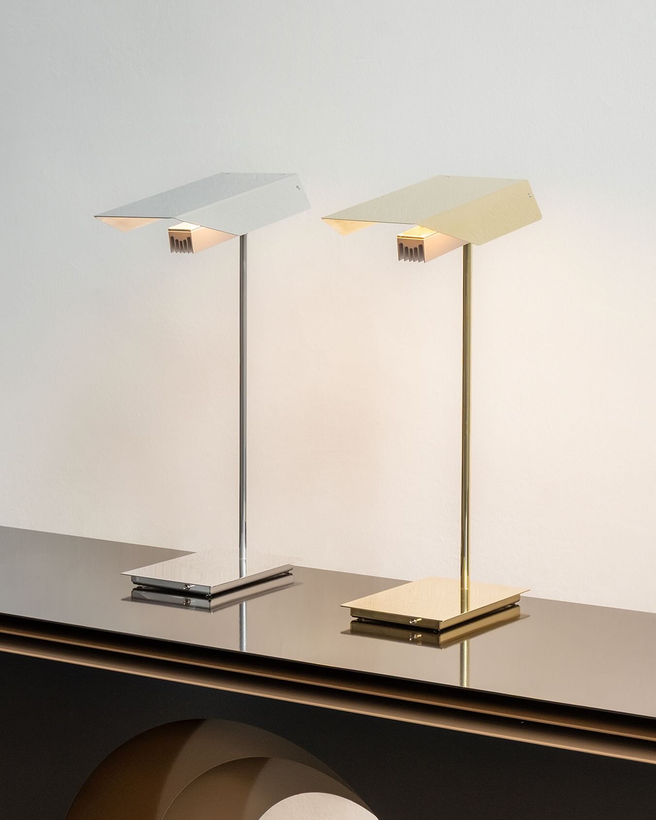 NEW NR5 lamp series
In its form, the table lamp NR5 is reminiscent of a classic library lamp and at the same time recalls Robot „Number 5“ from the 1980s film “Number 5 is Alive!”. Polished brass and polished aluminium accentuate its character – linear and slightly robotic. The head of the table lamp is movable. The reflector creates a clear light and emphasises the technical design. The toggle switch is located at the base of the lamp and the cable is covered in luminous orange fabric. Designed and produced in Hamburg, Germany.