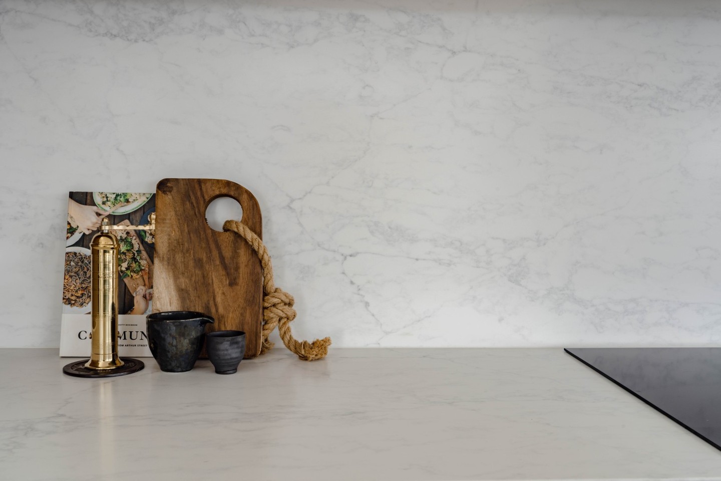 We love using the stone up the splashback for a luxurious aesthetic that's easy to clean too.
Depending on the cuts of your slab, you may find you have enough for the full splashback, but partial coverage is also fine! You can run your splashback stone part way up the back wall and include a little ledge for storing oils / salt and pepper.
Depending on the height your stone reaches, you can plaster or tile the top section. 