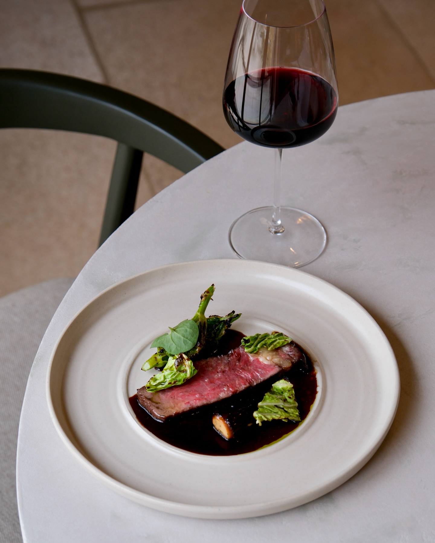 Dry aged Longhorn ribeye with chicken-stuffed morel, grilled Alexander hearts, and a beef sauce seasoned with beef garum.