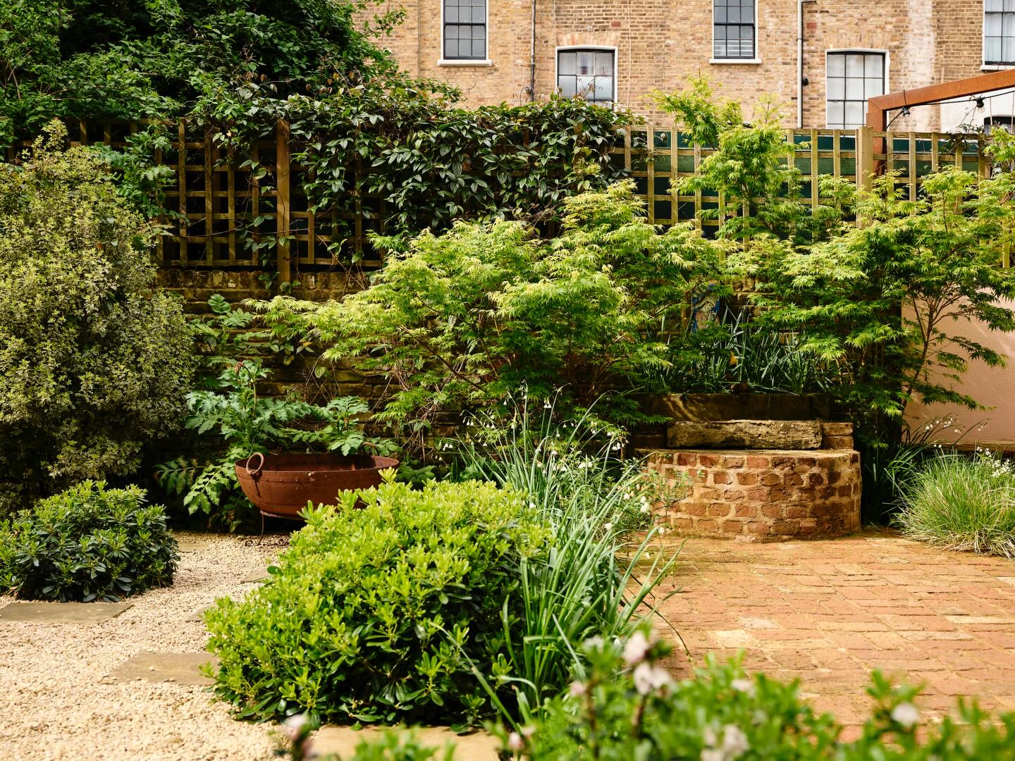 Pittosporum tobira and Leucojum ‘Gravetye Giant’, set against a classic basketweave brick and gravel surround. Photography by @dean.hearne #landscapephotography #gardenphotography #tuliplandscapes #springgardens