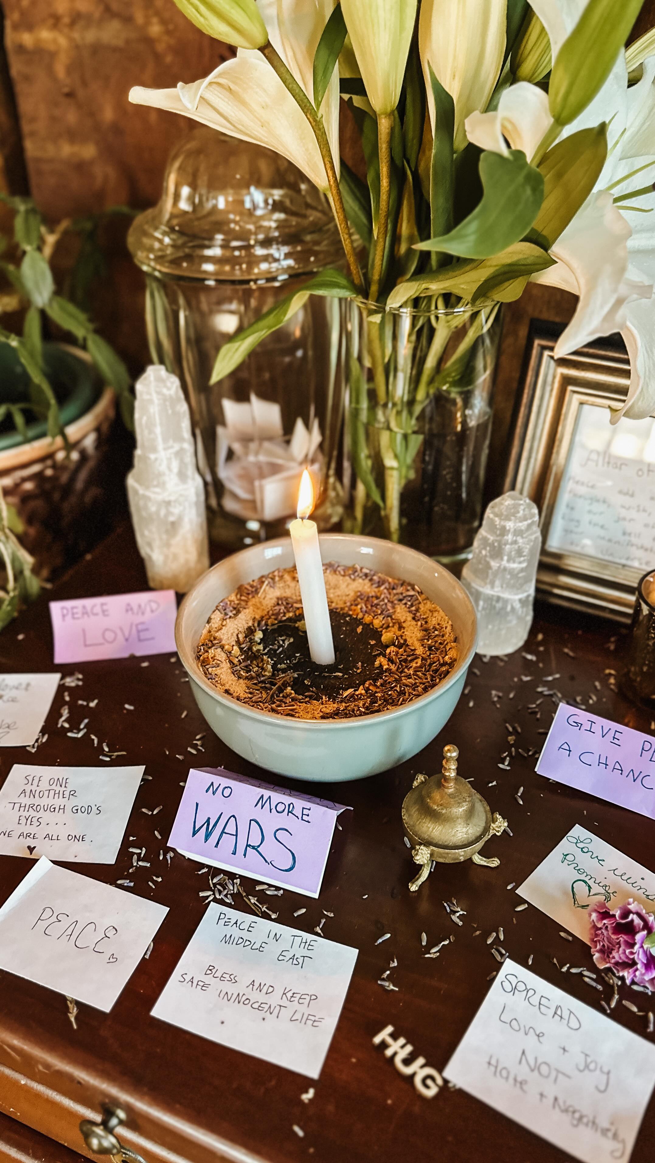 🕊️🔔 Altar of Peace ☮️✨
Witches gather, let your voices rise,
Hear the call of our ancestors’ cries.
From earth to sky, let our intentions fly,
May peace take root, and never die!
Inside the Ancestry Room at Tea & Tarot, is an altar devoted to focusing our communi-tea’s energy to bestow peace to our world. At its center, lilies bloom in quiet remembrance, surrounded by a bowl of chamomile, lavender, and nettle, each chosen with care to soothe, heal, and protect. A white candle stands to harness our collective thoughts and feelings, surrounded by black salt to protect and transmute our manifestation.
The altar collects our shared intentions… an end to violence, a call for no more wars, and a future where every life is valued and free from oppression, with healing and unity guiding the way. It echoes a dream witches have long stood for, a world where we may choose our own faith, speak in our authentic voices, and live without fear. Each note left behind, each whispered wish, becomes part of that future taking form.
All are invited to join in our sacred space, even if just for a moment, to imagine. To breathe deeply. To dream of a world without violence, where love leads and all beings are held in safety and care. And when you are ready, ring the bell and cast this spell of peace out into the universe 🔔✨
#TeaAndTarot #ImaginePeace #CTWitch #Activism #HollisticHealing