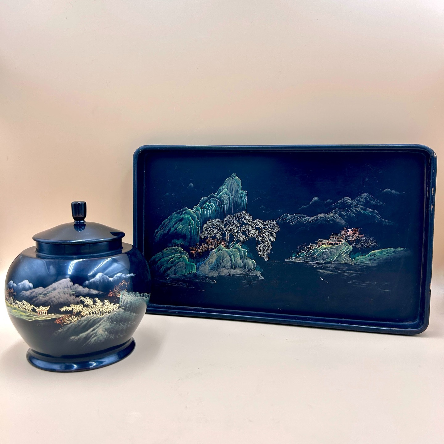 🟢 DOSTĘPNY | Zestaw lakowy, Chiny, l. 80 XX w.
Klasyczny zestaw z chińskiej laki (tzw. Chinese export lacquer) z amofrą/ginger jarem na herbatę oraz tacką, która nada się na ceremonię gongfu, choć nie jest to jej oryginalne przeznaczenie.
Ginger jar ma piękne czerwone wnętrze.
Dekorację stanowi pejzaż typu shan shui (góry i woda), z charakterystycznymi stromymi formacjami skalnymi, stylizowanymi drzewami i pawilonami, wykonany w technice malarskiej z użyciem jasnych pigmentów i złocenia na ciemnym tle. Kompozycja ma bardziej „graficzny”, linearny charakter niż w japońskim lakiernictwie i nawiązuje do chińskiej tradycji malarstwa pejzażowego, lecz w uproszczonej, dekoracyjnej formie.
Ginger jar: stan bardzo dobry z rysami na podstawie.
Tacka: stan dobry, uszkodzenia rantu uchwycone na zdjęciach.
Wymiary
Ginger jar: 16 cm x 9 cm
Tacka: 31 cm x 19 cm x 2 cm
120 PLN za zestaw + 20 PLN koszt wysyłki