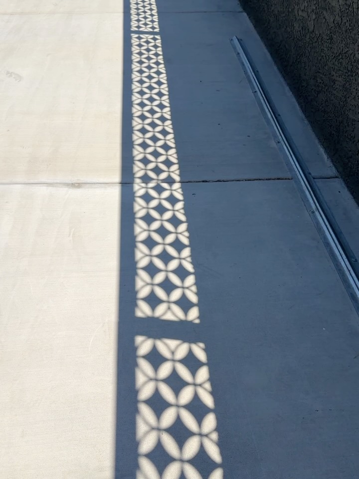Casting shadows with this open breeze block style wall topper finished in matte black powdercoat. This topper adds style, privacy, and security to this homes front yard.