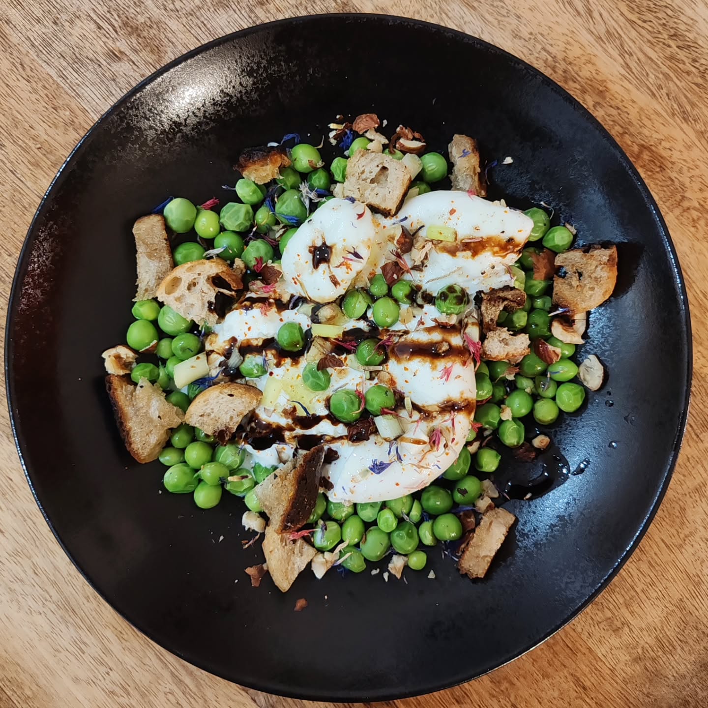 Burrata di bufala, petits pois frais, croûtons, noisettes torréfiées, huile de mandarine, velours de balsamique, piment d'Espelette et fleurs de bleuets séchées 💚