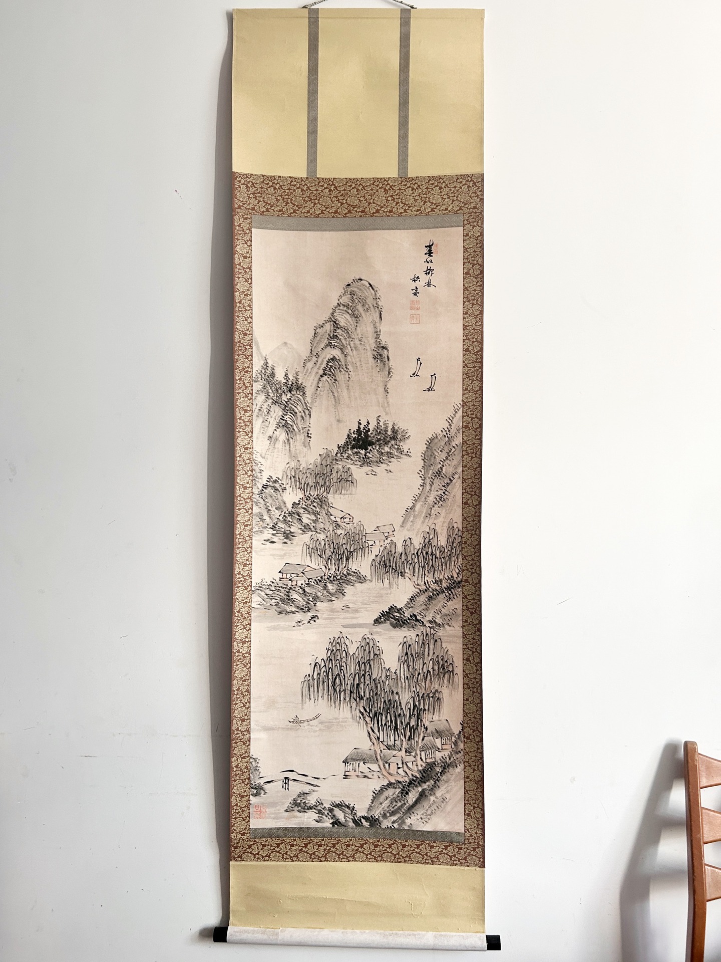 🟢 DOSTĘPNY | Klasyczny pejzaż typu shan shui by 朱樵 Zhu Qiao, Chiny, lata 1970-80.
Klasyczny pejzaż typu shan shui (山水), wykonany tuszem na papierze, przedstawiający idealizowany, literacki krajobraz górsko-rzeczny.
Kompozycja jest wertykalna i zbudowana według tradycyjnej zasady „wędrówki oka”: od dolnej partii z rzeką i zabudowaniami wiejskimi, poprzez strefę środkową z gęstymi zaroślami i pagórkami, aż po dominujący masyw skalny w górnej części. Góry ukazane są przy użyciu miękkich, warstwowych pociągnięć pędzla i techniki rozmycia (cunfa), co nadaje im organiczną, niemal falującą strukturę; ich zbocza porastają stylizowane drzewa, malowane punktowo i skrótowo. W dolinie widoczne są niewielkie domostwa o prostych dachach, częściowo ukryte wśród drzew, co podkreśla ideę harmonijnej koegzystencji człowieka i natury.
Całość utrzymana jest w oszczędnej estetyce wenrenhua. Inscription i pieczęcie w górnej części pełnią zarówno funkcję autorską, jak i integralny element kompozycji, równoważący wizualnie ciężar masywu górskiego.
Autorem obrazu jest 朱樵 Zhu Qiao, XX-wieczny malarz tuszem.
Stan bardzo dobry - drobne plamy i przetarcia widoczne na zdjęciach. Zwój został poddany renowacji.
Wymiary: 180 cm x 50 cm
1100 PLN + 20 PLN koszt przesyłki