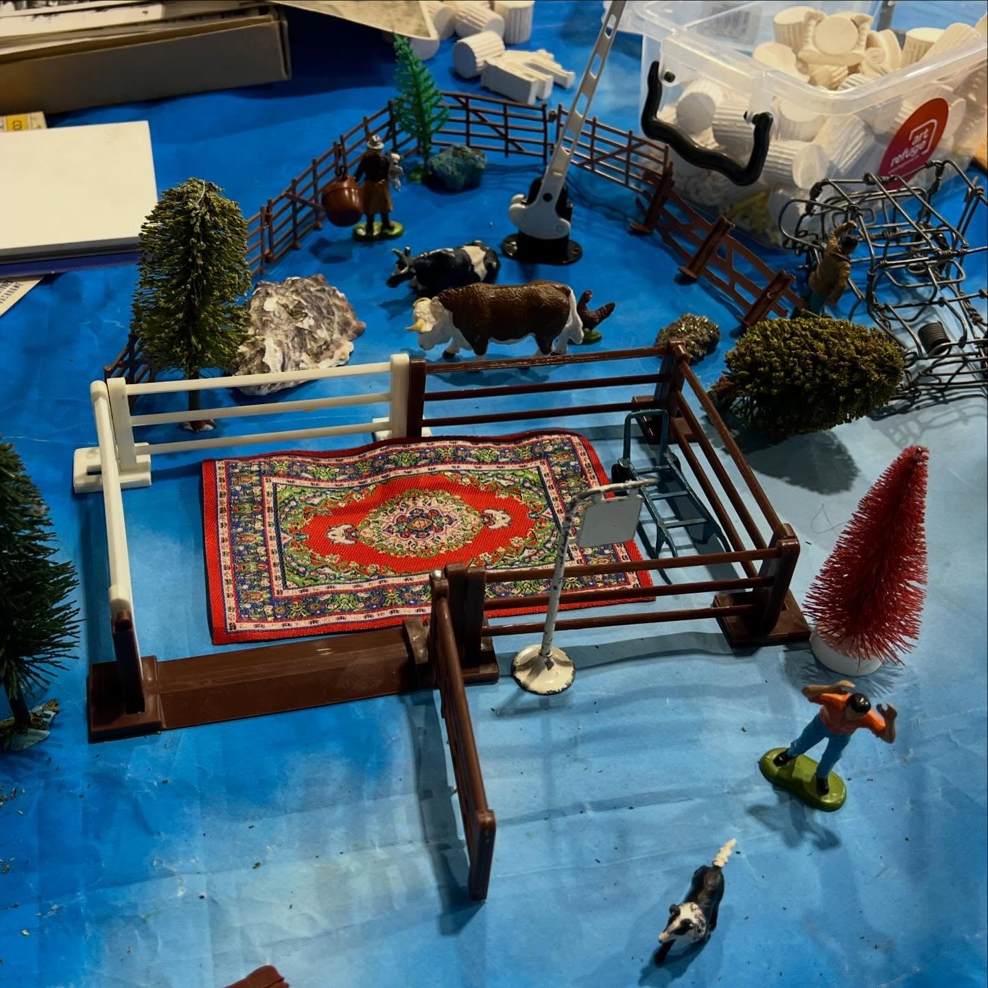 WATER DROPS ON A PETAL
Calais 15.04.2026
On the 3rd anniversary of the start of the civil war that is raging in Sudan, more reports are emerging about the horrifying scale of the war and dislocation. In the midst of the world’s worst humanitarian crisis, millions of Sudanese citizens are displaced, some outside the country, forced from their homes.
Today we travelled once again to Calais. Arriving at @calais.exilessc we found it carefully organised in anticipation of the large community of young people who soon filled it for the afternoon, the vast majority from Sudan, and also South Sudan. Several told us that they come from war torn areas of Darfur and El-Fashir, some speaking of travelling hundreds of the miles of their journey by foot. Several of the 60 or so young people who joined The Community Table were as young as 14 or 15.
We set up the table in the main space, the clouds and green cloth providing the ground. As the day centre filled, so did the table. Multiple narratives were played out, some articulated to us and some between the young men themselves. There was a sense that the table, materials and curation were very well used. Above all, what struck us was just how willing the young men were to play, while we also noticed the care and friendship shown for eachother.
Today the table was rich with activity: knitting - ‘my sister taught me’; building houses & gardens; trying out the typewriter, mostly names & today’s date; attempting to build the tallest tower; playing with scale; working something through with postcards & miniature figures; requesting Charles Dickens be read aloud; wondering about what seasons feel like.
One slightly older young man wanted to talk about the table: this table is amazing, thank you for being here. Looking across at 3 teenage boys carefully building roofs & environments for their houses he commented: They need to de-stress, even when they have to go back to their difficulties, they will take this time away with him.
Bringing things down to something very small perhaps offers a moment or two of respite, like one young man’s wonder at the water drops on a flower’s petals as seen through the slide viewer.