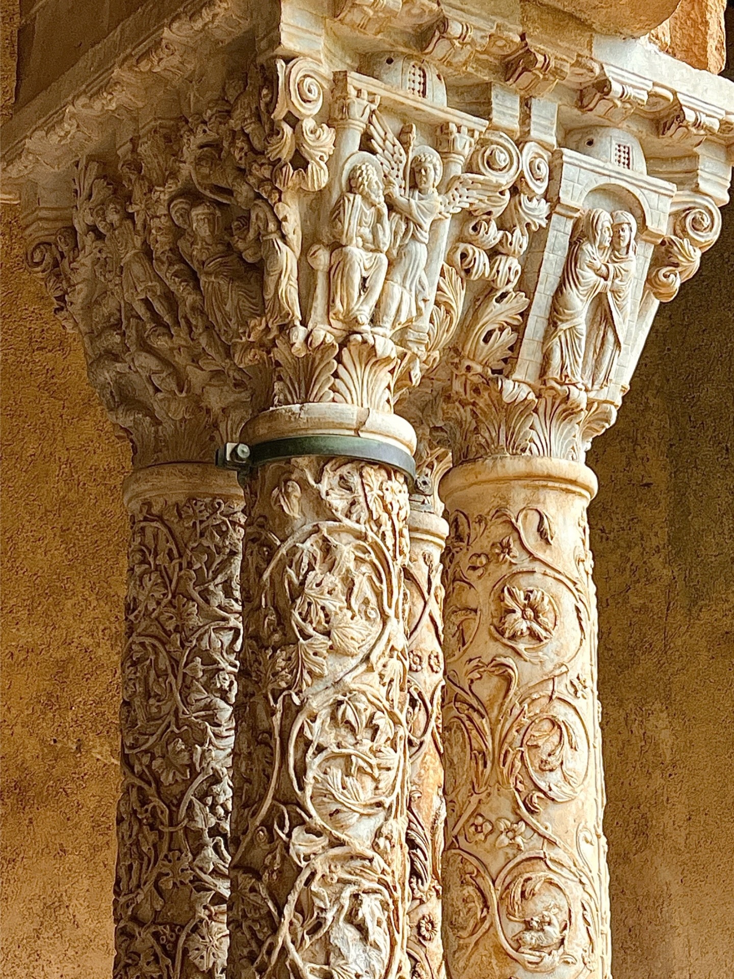 Der Kreuzgang des früheren Benediktinerklosters von Monreale erinnert ein wenig an die Alhambra. Die besten Steinmetze aus aller Welt und aller Religionen schufen dieses Meisterwerk im 12. Jahrhundert.
Über 200 paarweise angeordnete Säulen tragen die Arkadenbögen und jedes Säulenpaar ist ein Unikat: Manche sind glatt, andere kunstvoll geschlagen oder mit Mustern verziert, die golden oder dezent bunt leuchten.
Die Säulen und ihre Kapitelle erzählen Geschichten und stecken voller Symboliken, die bis heute noch nicht vollständig entschlüsselt sind.