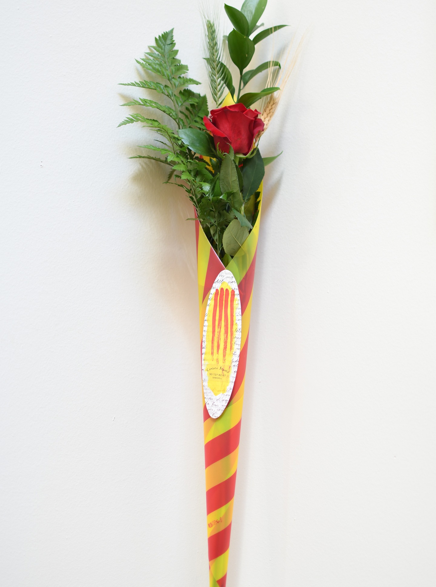 ROSA CONO SENYERA
La rosa cono senyera combina tradició i presentació, amb un format pràctic i molt visual inspirat en Sant Jordi.
Composició del producte:
• Rosa vermella (Freedom / Red Naomi / Explorer – 80 cm segons disponibilitat)
• Verds de ruscus i leather
• Espiga natural verda
• Espiga seca rosada
• Cono amb disseny de la senyera
• Punt de llibre de la casa
Reserva-la a la web.