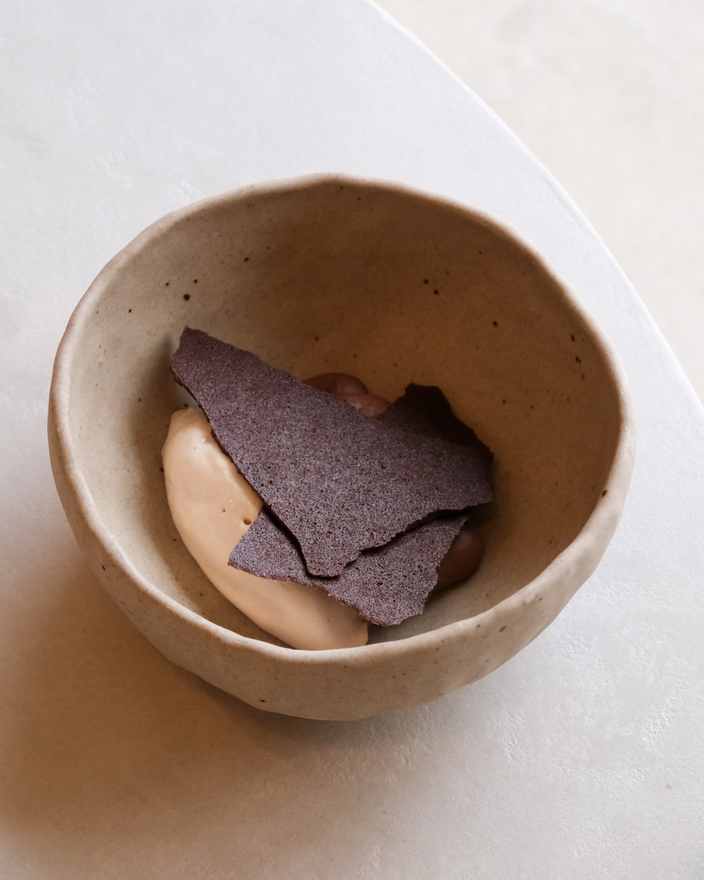 A rich Chocolate Crèmeux topped with crunchy chocolate crackers, with a creamy hazelnut ice cream, and toasted chopped hazelnuts layered beneath.