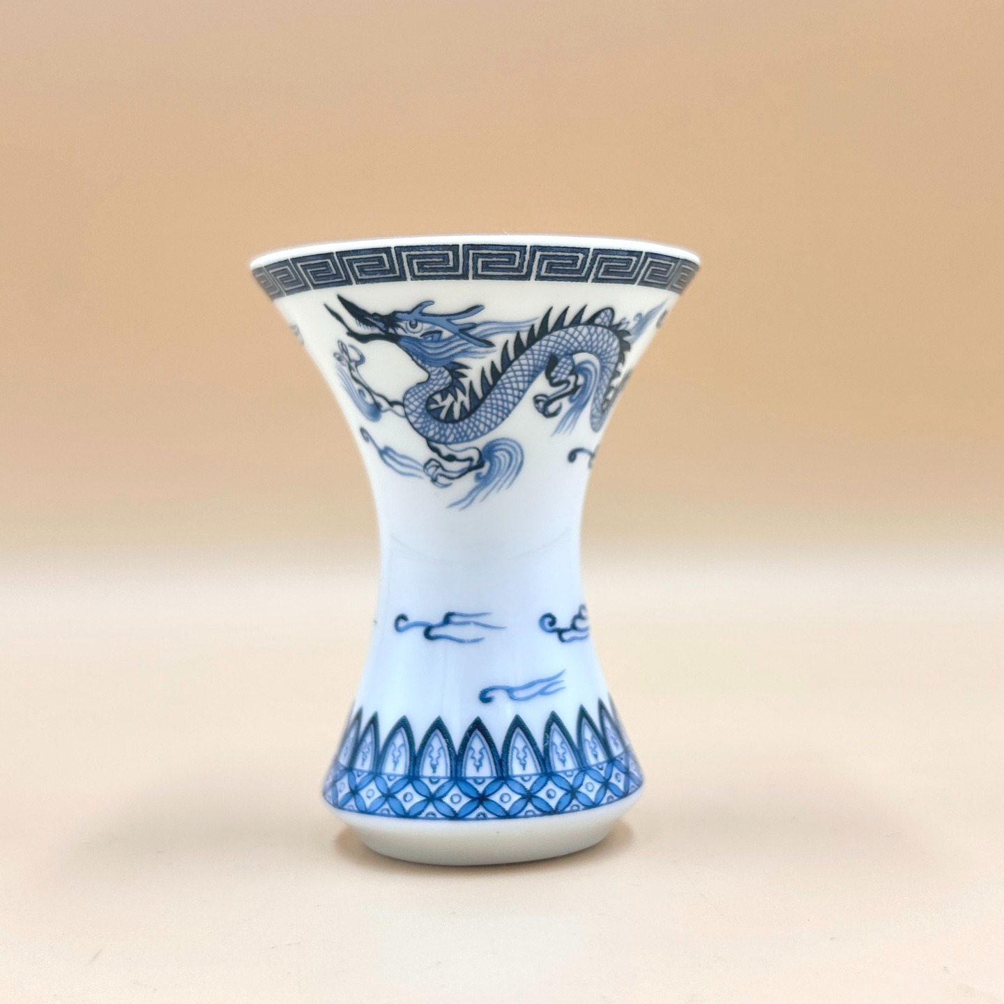 🟢 DOSTĘPNY | Mikro wazonik ze smokiem, Chiny, lata 80.-90.
To niewielki, współczesny wazonik porcelanowy typu miniature / micro vase, wykonany w Chinach w stylistyce qinghua (blue and white), nawiązującej do klasycznej porcelany dynastii Ming i Qing.
Dekorację stanowi stylizowany smok o wydłużonym, dynamicznie wijącym się ciele, ukazany wśród obłoków, symbolizujący władzę, siłę i pomyślność; całość wykonana została podszkliwnie kobaltem, z użyciem zróżnicowanej kreski i tonalnych przejść imitujących tradycyjne malarstwo pędzlem. Kompozycję uzupełniają geometryczne bordiury.
Wazonik dekorowany techniką transfer print.
45 PLN + 15 PLN koszt wysyłki