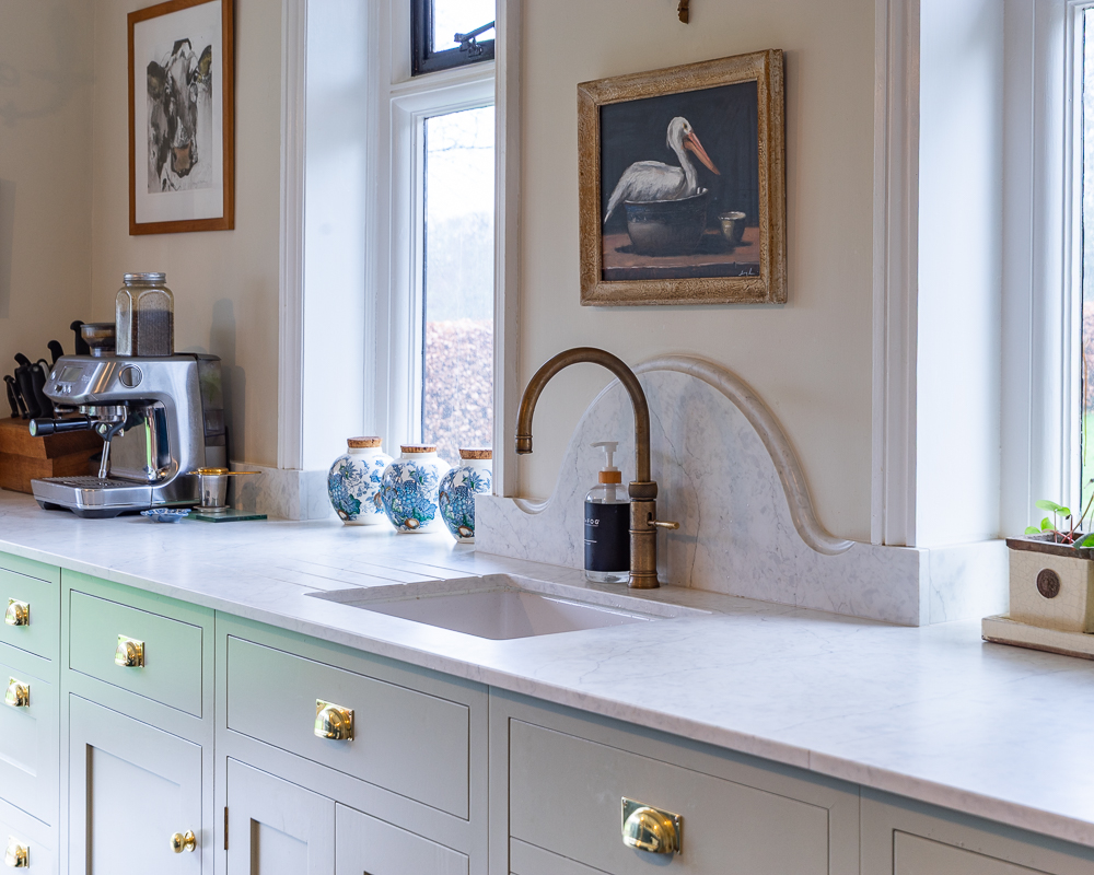 Sometimes it is the quieter details that give a kitchen its character. In this space, the sink run was designed to feel more than purely functional, with the shaped stone upstand bringing a softer architectural line to the elevation. Set against painted cabinetry and warm brass fittings, it gives the whole composition a sense of charm, depth, and individuality. #BespokeDesign #KitchenInspo #InteriorDesign #ModernLiving