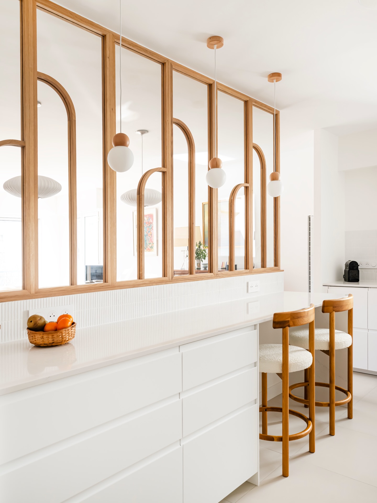 Un jeu d’équilibre entre ouverture et intimité.
Pensé comme une respiration au cœur de l’appartement, cet espace cuisine s’articule autour d’une verrière en bois dessinée sur mesure. Ses lignes verticales et ses arches délicates instaurent un rythme, presque architectural, qui structure la perspective sans jamais l’alourdir.
La lumière circule librement, révélant une palette volontairement épurée où le blanc dialogue avec la chaleur du bois. Chaque élément trouve sa place avec justesse : des suspensions sphériques qui ponctuent l’espace, au plan snack qui prolonge naturellement les usages.
Un projet où la simplicité apparente révèle un travail précis des proportions, des matières et des détails.
#designminimaliste #parisarchitecture #decohautdegamme #architectedinterieur #livingwithstyle
Sous le regard du talentueux @julien_pepy_photographe
Verrière réalisée par @atelier_georges_agencements
Plan de travail en silestone de @cosentino_france façonné et posé par @easyplandetravailsurmesure
Chaises hautes @sklum
Applique @schwung.design
Crédence et sol @ceramicafusaro
Parquet @decoplusparquets