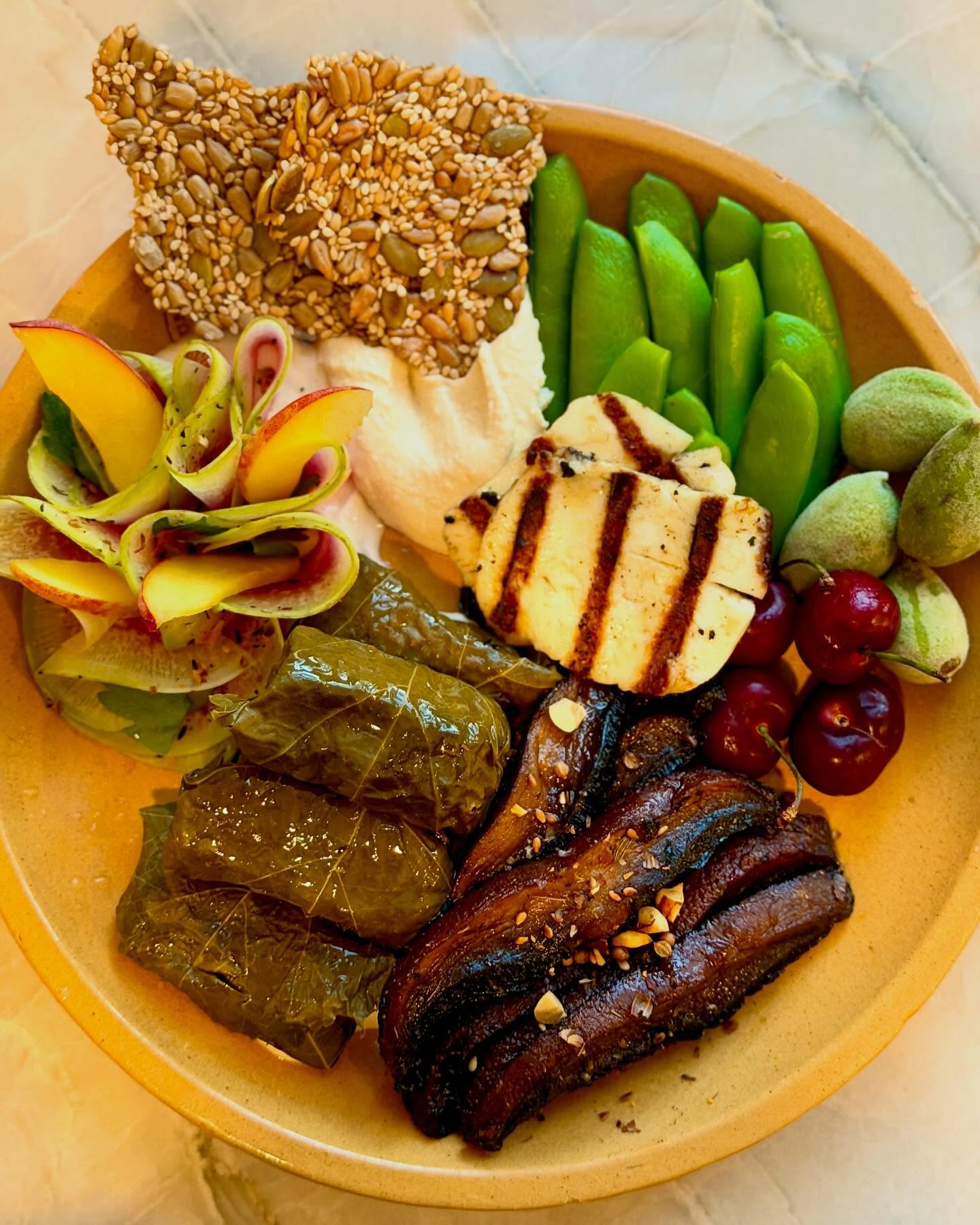 #privatechef plates Entry 08: Mezze (Californian Special Mix)
Sarma (Turkish) / Dolmades (Greek) - thank you @verymuchindeed for the naming lesson. Grape leaves don’t come pre-rolled. The filling has to be seasoned right. The roll tight enough to hold, loose enough to let the rice expand. Then you layer, and you wait.
Also: Mushroom shawarma · Hummus · Seed cracker (all from scratch). Grilled halloumi.
Farmer’s market: Radish & peach with sumac-za’atar blend · Green almonds · Sugar snap peas · Early Glen cherries
New territory for me. Learned it, tested it, executed it for a client whose family knows this dish. They approved.
#privatechefla #sarma #dolmades #mezze