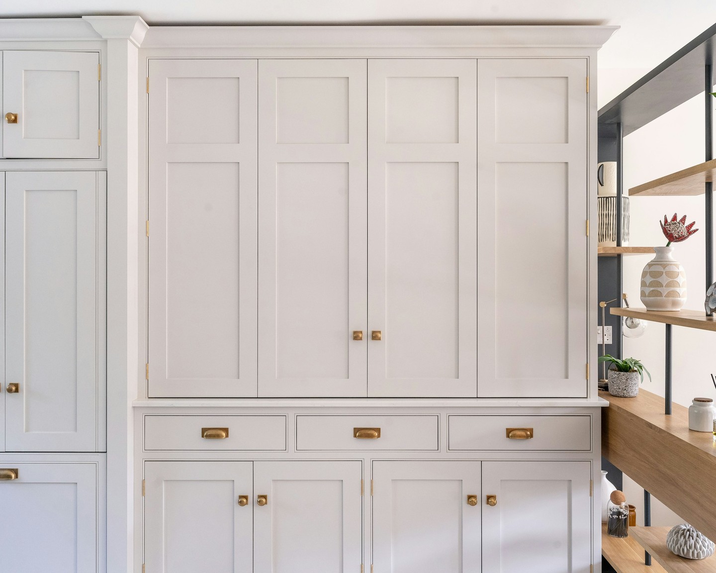 This white Shaker kitchen features a breakfast pantry with bi-fold doors, offering generous storage while keeping the space neat and well organised. #BespokeDesign #KitchenInspo #InteriorDesign #ModernLiving