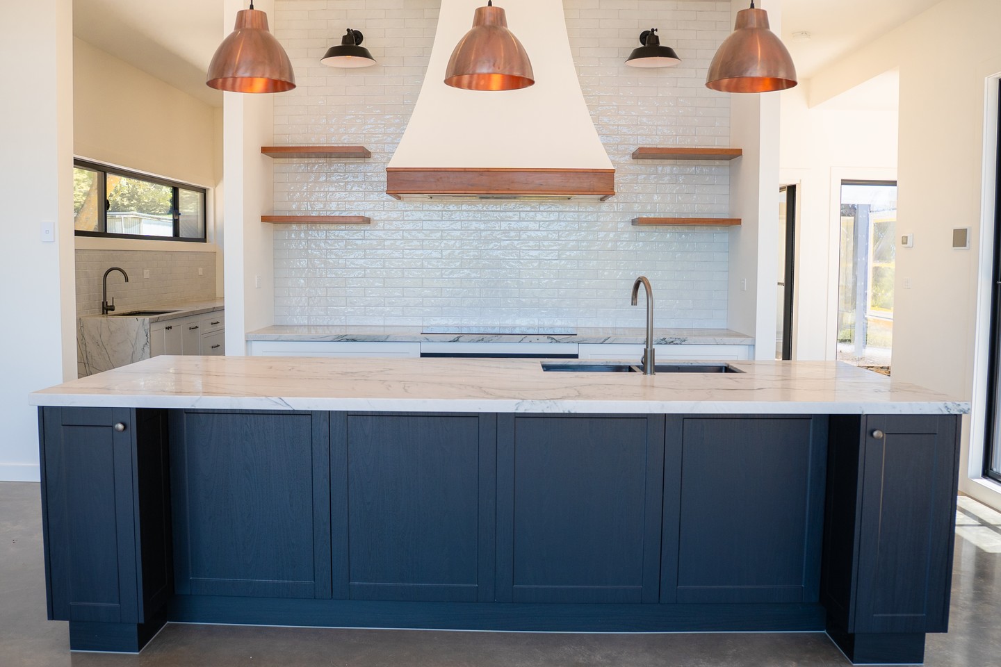 The Newham kitchen is compact by design but covers every base - a generous island with seating, stone benchtops, open timber shelving and copper pendant lighting that signals exactly how this space gets used. A kitchen laid out for people who cook with guests in the room.
#buildtrendhomes #macedonrangesbuilder #newham #kitchendesign #customhome
