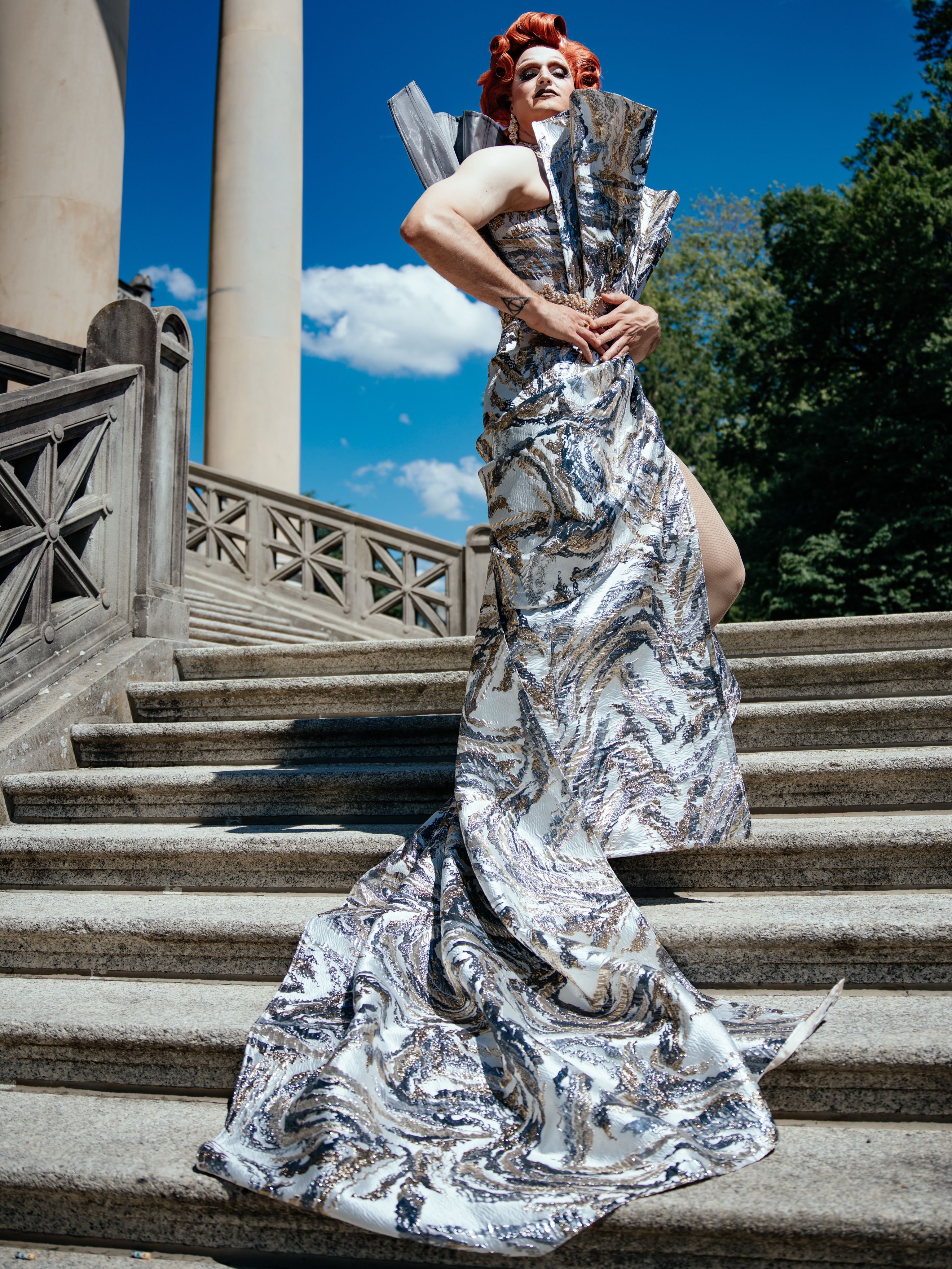 If grandeur had a staircase, I suppose this would be the entrance.
Silver woven like liquid marble, a silhouette sharp enough to start rumours, and a Winterthur summer sky dramatic enough to deserve me.
Création by @maisonoran
Photographed by @steve_w_grams
#DragRoyalty #FashionEditorial #CoutureArt #BaselCulture #QueerElegance