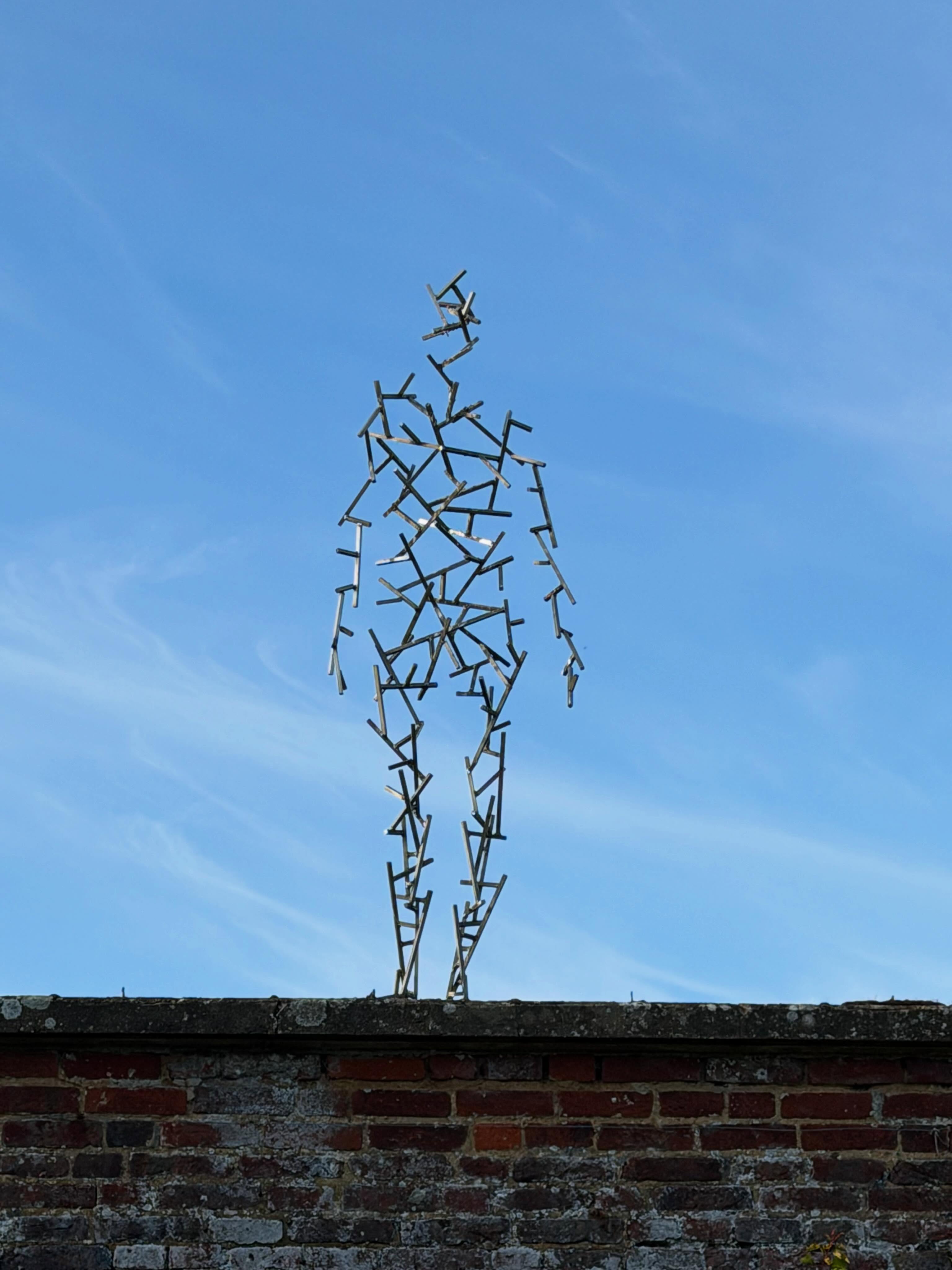 An Antony Gormley figure standing upon the Walled Garden walls
