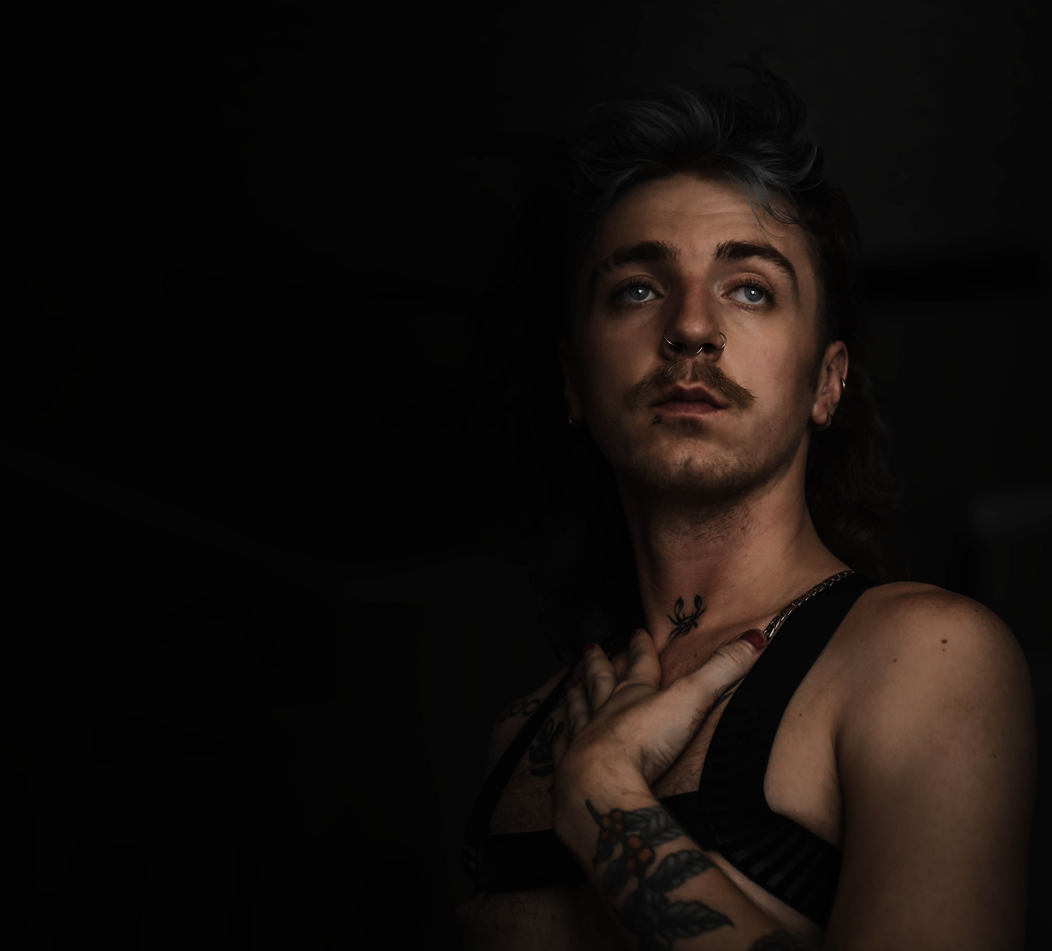 As he stands in the quiet, the darkness wraps around him like a cloak, transforming solitude into a mesmerizing canvas of inner strength and sensuality.