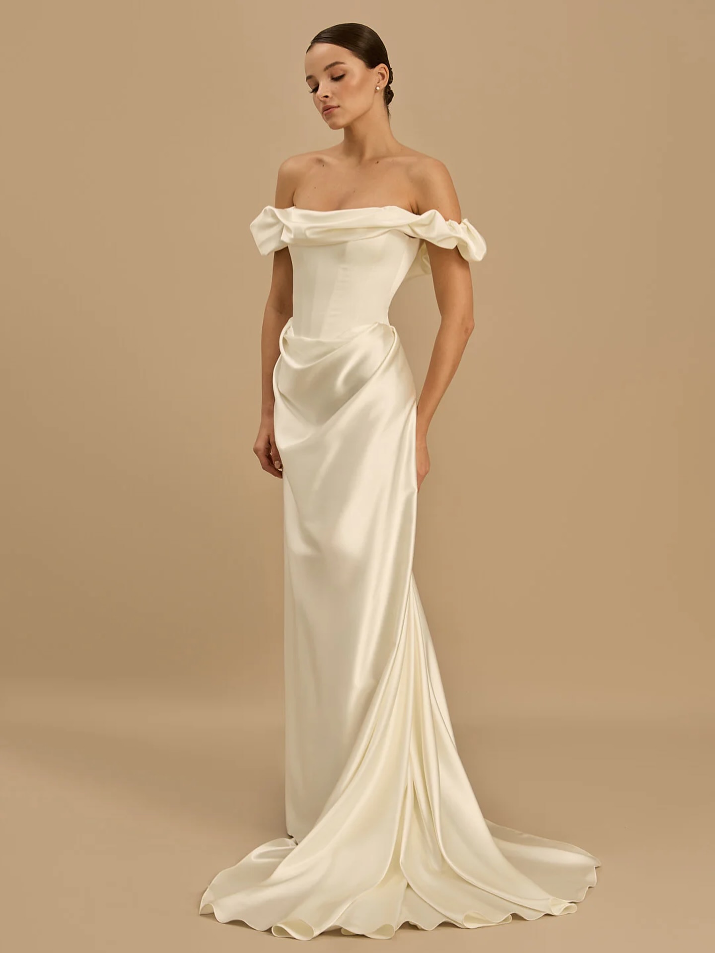 Celine by Rouvell *COMING SOON*
For the bride who wants simplicity without disappearing into it. Celine pairs a softly draped off-the-shoulder neckline with sculptural detailing through the bodice and hips, creating a silhouette that feels effortlessly elegant.
Cut in luminous satin with a fluid skirt and sweeping train, she’s proof that a plain dress never has to mean boring. Modern. Refined. Unforgettable.
