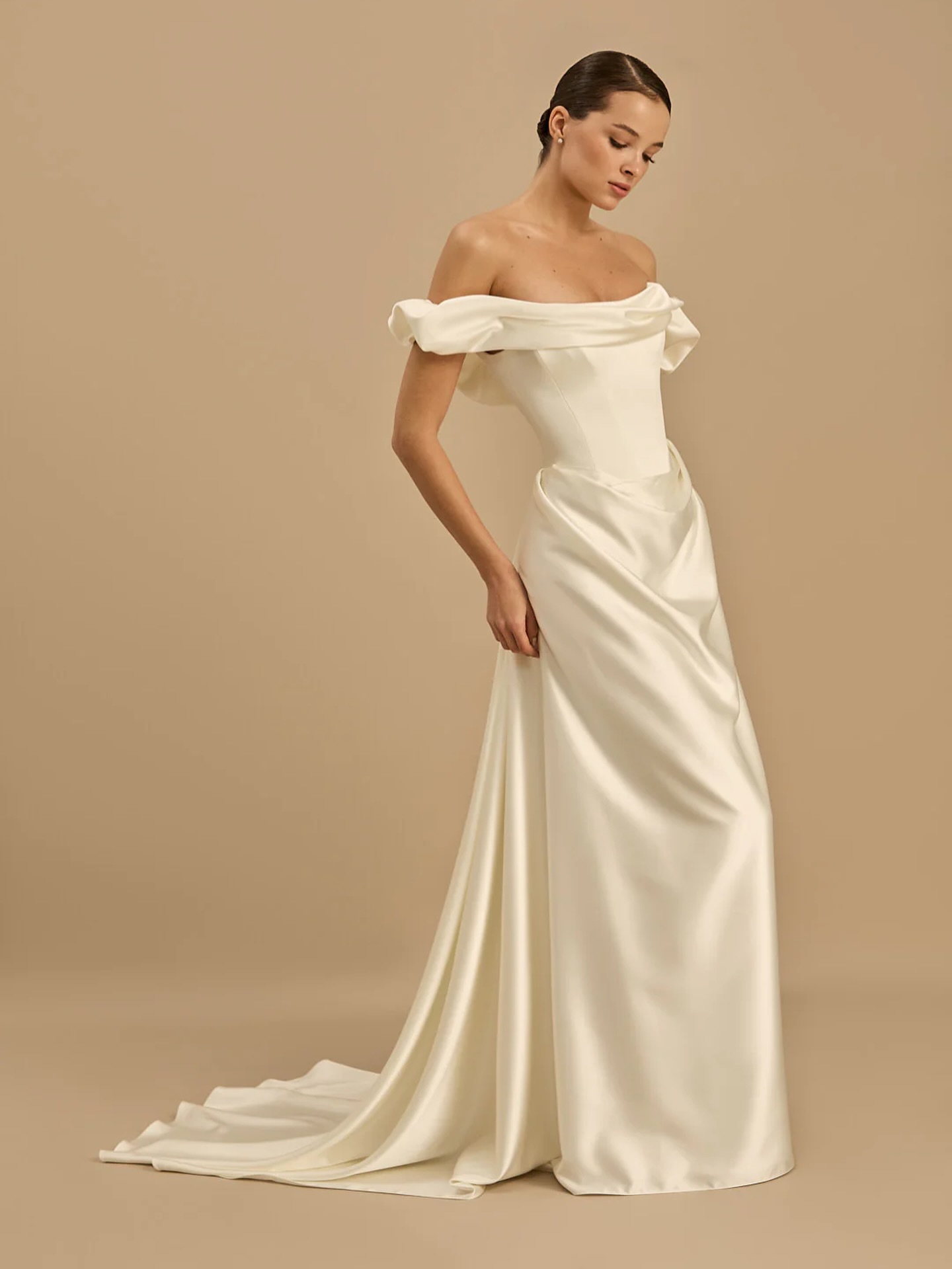 Celine by Rouvell *COMING SOON*
For the bride who wants simplicity without disappearing into it. Celine pairs a softly draped off-the-shoulder neckline with sculptural detailing through the bodice and hips, creating a silhouette that feels effortlessly elegant.
Cut in luminous satin with a fluid skirt and sweeping train, she’s proof that a plain dress never has to mean boring. Modern. Refined. Unforgettable.