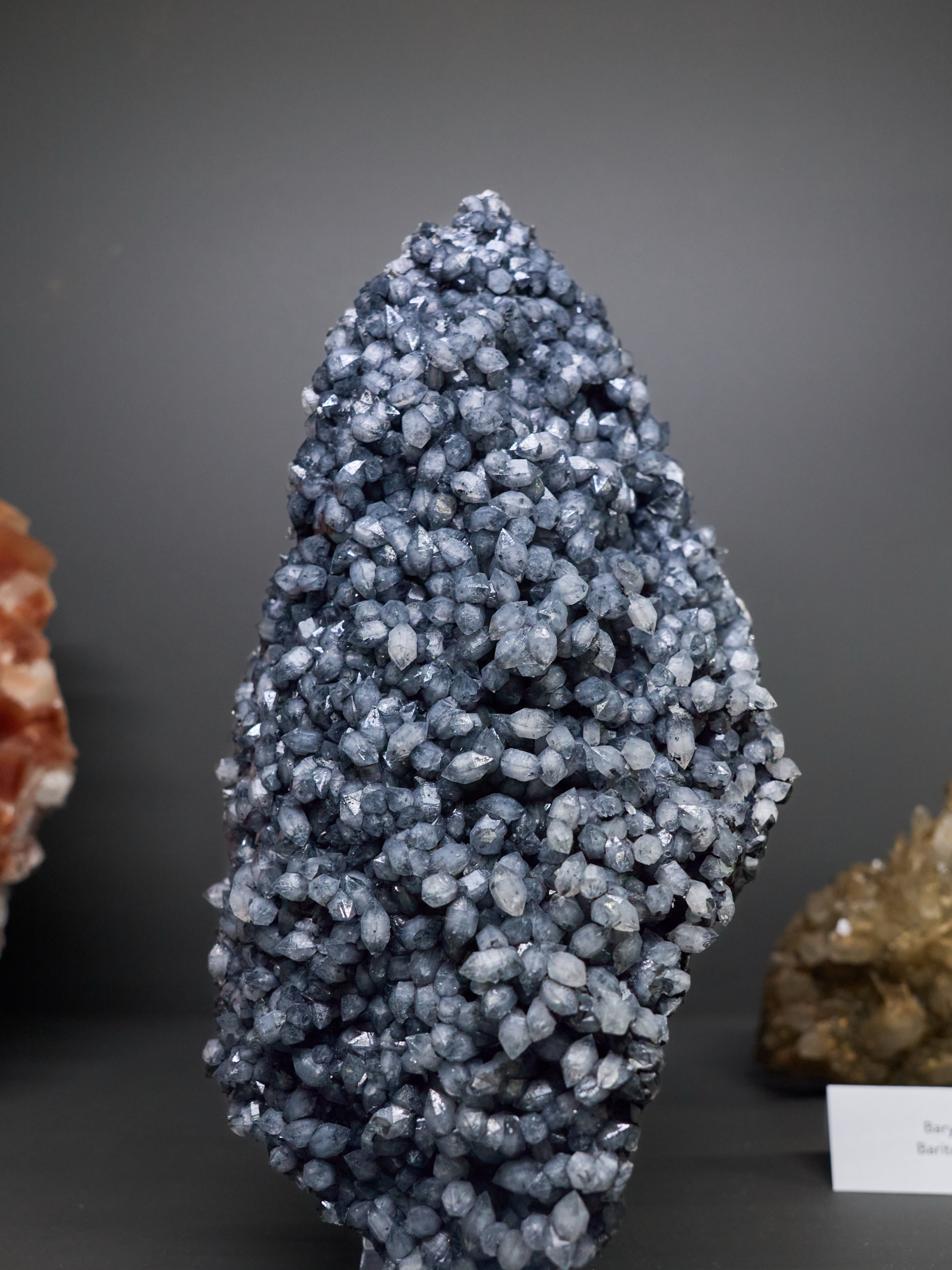 MINERAL MONDAY ✦ PLUMOSITE IN QUARTZ
At first glance, it almost looks like a cluster of tiny silver-blue crystals.
But take a closer look…
This remarkable specimen is known as Plumosite in Quartz. The countless quartz crystals are filled with delicate inclusions that give them their distinctive smoky blue-grey appearance and shimmering character.
The closer you look, the more details emerge – hundreds of perfectly formed crystals, each unique, yet together creating something extraordinary.
Fun fact: Some mineral specimens reveal their beauty from afar. Others only unveil their secrets when viewed up close. This is definitely one of them.
Nature’s finest details are often the easiest to overlook.
📍 Discover this and thousands of other treasures in our Mineral Museum.
🎁 Looking for a unique piece for your home or a special gift? Visit our online shop and explore a carefully selected collection of minerals from around the world. Link in bio.
#mineralmonday #mineralmoments #mineralienhotel #quartz #plumosite