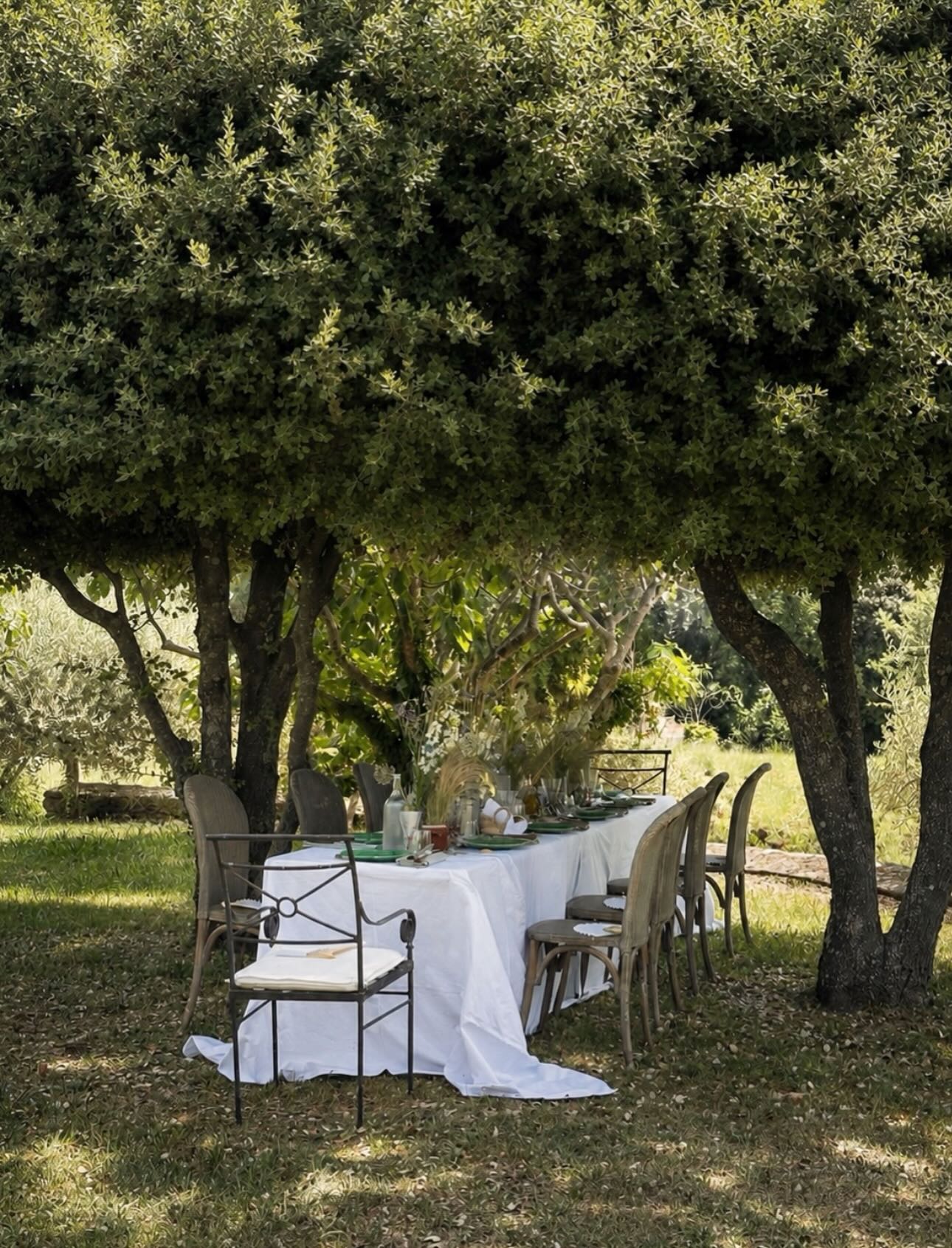 A simple lunch is elevated in the garden under the shade of the trees. Vintage cotton embroidered bedsheets from the brocante make the perfect tablecloth and the magic touch of @fleurs_d_arles 🤍