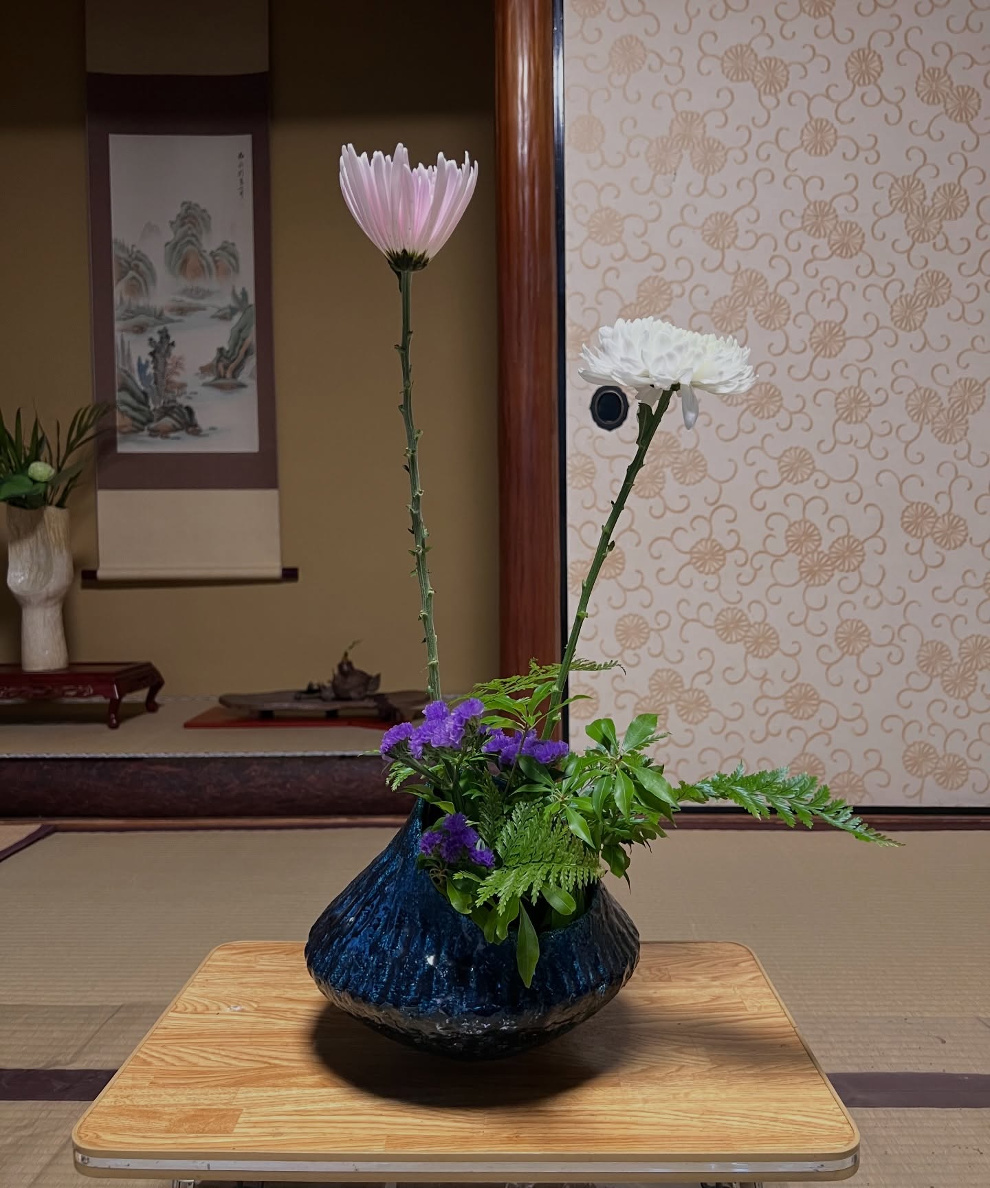 Playfulness, guided by harmony.
In ikebana, there is an important principle called kaki-sōō (花器相応) — creating an arrangement that harmonizes with the vase.
It means carefully considering the vase’s shape, color, size, and overall character, then choosing and arranging flowers that truly belong with it.
But harmony doesn’t mean playing it safe.
For this lesson, my teacher selected a deep indigo vase with a rounded form as the theme.
Respecting its calm, dignified presence, I let the pink and white chrysanthemums rise gracefully above it, while adding soft touches of purple statice to bring a sense of lighthearted playfulness.
When we respect the vessel, the flowers are free to express their own vitality.
Playfulness becomes meaningful because it is grounded in the fundamentals.
This arrangement reminded me of that once again.
遊び心も、花器相応も。
いけばなには「花器相応(かきそうおう)」という教えがあります。
花器の形や色、大きさ、雰囲気をよく見て、
その器にふさわしい花をいけること。
でも、それは決して「無難にまとめる」ということではありません。
今回の親先生からのお題は丸みのある深い藍色の花器。
その落ち着いた存在感に合わせながら、
ピンクと白の菊を高く伸びやかに立たせ、
紫のスターチスを添えて、軽やかな遊び心を加えました。
器を尊重するからこそ、
花も自由に生き生きと見えてきます。
遊び心は、基本があるからこそ生まれるもの。
そんなことを改めて感じた一作でした。
#ikebana
#sagagoryu
#japaneseculture
#kyoto
#flowerarrangement
