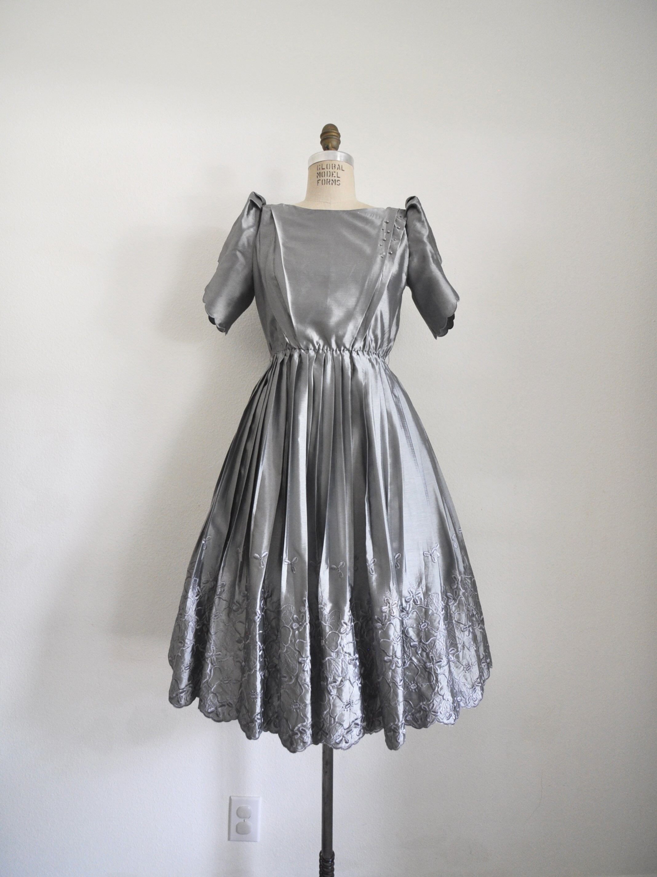 Link in bio to shop! Beautiful silver 1970’s dress. Fully lined, polyester, elastic waist, scalloped sleeves, pleated skirt, embroidered border hem. Bust: 34” Waist: 20-29” Length: 43” Shoulder to waist: 15”