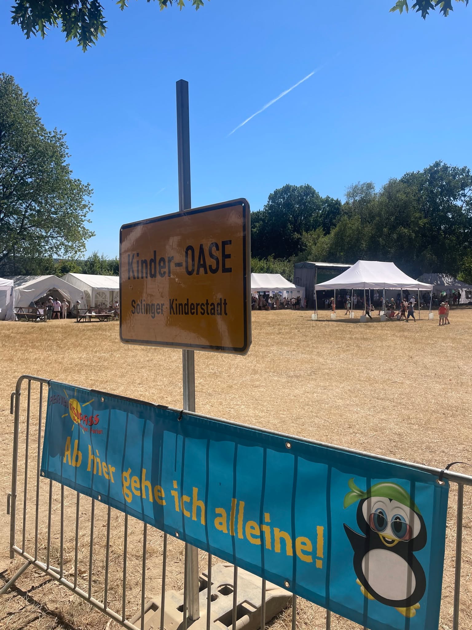 Zu Besuch in der Kinder-OASE
Was wäre, wenn Kinder ihre eigene Stadt bauen, Berufe ausprobieren, über Regeln entscheiden und dabei ganz nebenbei Demokratie lernen? Genau das passiert in der Kinder-OASE des Solinger Ferien(s)passes.
Wir waren vor Ort und haben mit den Verantwortlichen über die Arbeit, die Herausforderungen und die Zukunft der OASE gesprochen. Seit mittlerweile 8 Jahren ist sie ein wichtiger Bestandteil der Solinger Ferienangebote.
Ob als Stadtverwaltung, im Handwerk, in der Zeitung oder im OASEN-Stadtrat: Die Kinder übernehmen Verantwortung, treffen Entscheidungen und erleben, wie eine Stadt funktioniert. Dabei geht es um viel mehr als Beschäftigung in den Ferien. Es geht darum, Kinder ernst zu nehmen, ihnen zuzuhören und ihnen zu zeigen: Du bist wertvoll und kannst etwas bewegen.
Doch die OASE steht auch vor Herausforderungen. Die Finanzierung ist ein großes Thema. Mehr als 100.000 € müssen gestemmt werden, während ein Teil der Finanzierung über die Stadt abgesichert wird. Gleichzeitig stellt sich eine entscheidende Frage für die Zukunft: Was passiert mit dem Gelände? Die bisherige Nutzung ist nicht dauerhaft gesichert.
Für uns ist klar: Wenn sich am Gelände etwas verändert, muss die Kinder-OASE frühzeitig mit an den Tisch. Und auch bei der Finanzierung braucht es langfristige Perspektiven, damit dieses wertvolle Angebot nicht von Jahr zu Jahr um seine Zukunft bangen muss.
Die Kinder-OASE ist ein echtes Mosaik unserer Stadtgesellschaft: vielfältig, engagiert, demokratisch und von Menschen getragen, die ihre Zeit investieren.
Wir finden: Solingen sollte dieses Engagement nicht nur wertschätzen, sondern langfristig ermöglichen und absichern. 🧡
Redaktionelle Info: Unser Beiratsmitglied Georg Schubert hat für uns den O-Ton vor Ort aufgenommen. Die Kinder-OASE kennt er dabei nicht nur aus politischer Perspektive, sondern engagiert sich selbst ehrenamtlich bei „Gräfrath hilft“ in der Kinder-OASE.