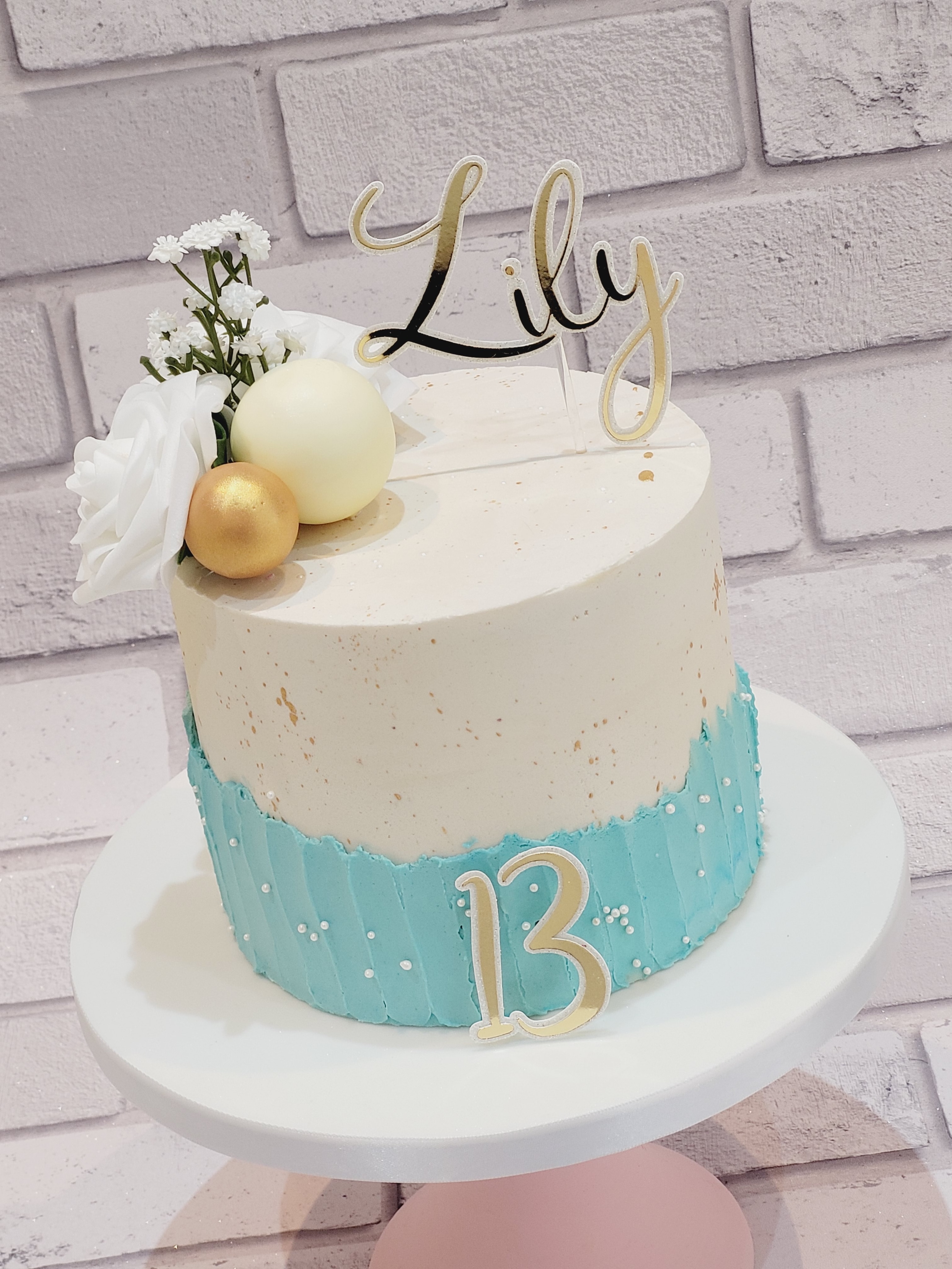 ✨ A beautiful 13th birthday cake for Lily ✨
A soft and elegant design featuring crisp white buttercream, delicate baby-blue textured detailing and subtle gold splatter. Finished with pretty white flowers, gold and ivory spheres, pearl details and a stunning personalised “Lily” topper. 🤍💙✨
A timeless and elegant cake for a very special 13th birthday! 🎂
#BirthdayCake #13thBirthday #CelebrationCake #CakeDesign #NorthWalesCakes