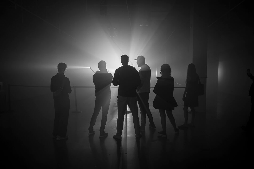 Saved the best for last. This is my favorite photo from Mode Festival — Satellites by Nonotak.
I was so locked into the light itself, trying to work out the best way to capture it, that I almost missed the shot that was actually right in front of me. @krisneedscoffee pointed out that the crowd — reduced to pure silhouette against the haze — was the real composition. She was right. Special thanks to Kris for spotting it before I did.
Nonotak (@nonotakstudio) is Noemi Schipfer and Takami Nakamoto, a Paris-based duo working in light, sound, and space — and Satellites wasn’t just visual, it was sonic. Standing in the lights with the sound design wrapping around us, I felt like I’d stepped straight into the original 1982 Blade Runner.
This one is inside a building, but it doesn’t feel like it — and that’s got me thinking. I’m falling back in love with black and white, and finding my way into street photography almost by accident. Turns out what makes an image feel like “street” isn’t the pavement, it’s candid human gesture caught inside a scene you didn’t stage. Silhouettes, strangers, a moment nobody posed for — that’s the same instinct whether it’s a sidewalk or a fogged-out gallery floor.
📍 Mode Festival — @modebyflickr
✨ Installation: Satellites by Nonotak — @nonotakstudio
#ModeFestival #Satellites #StreetPhotography #LightArt #Photography WanderlustPhotography